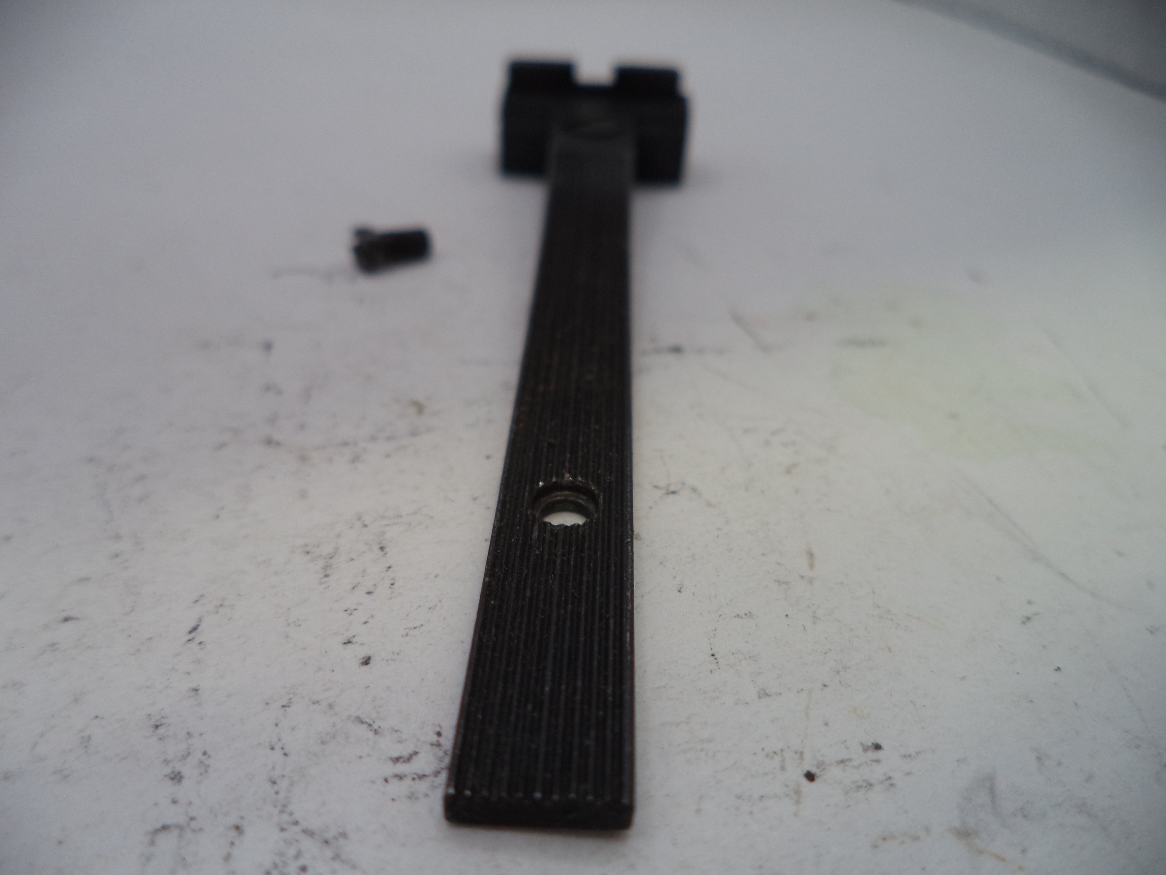Black metal tool on a white surface with visible wear