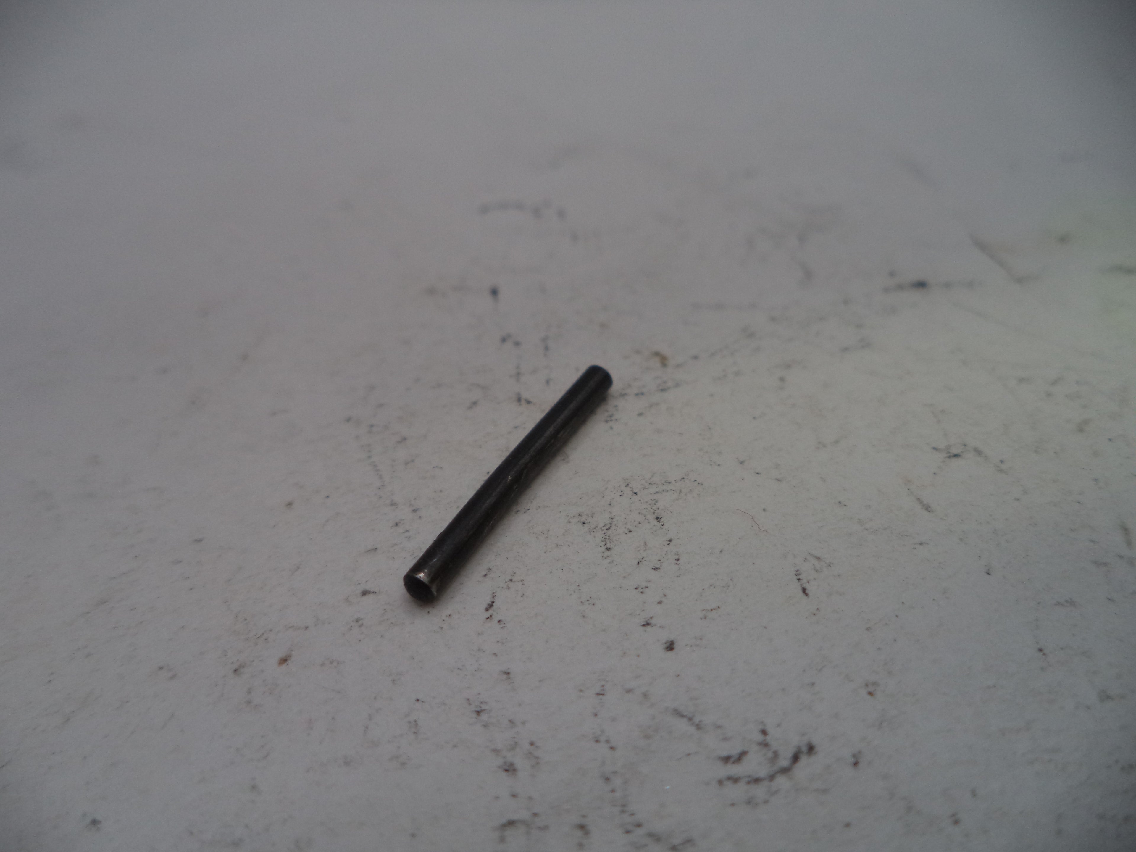 Small black cylindrical object on a white surface with visible dirt and stains.