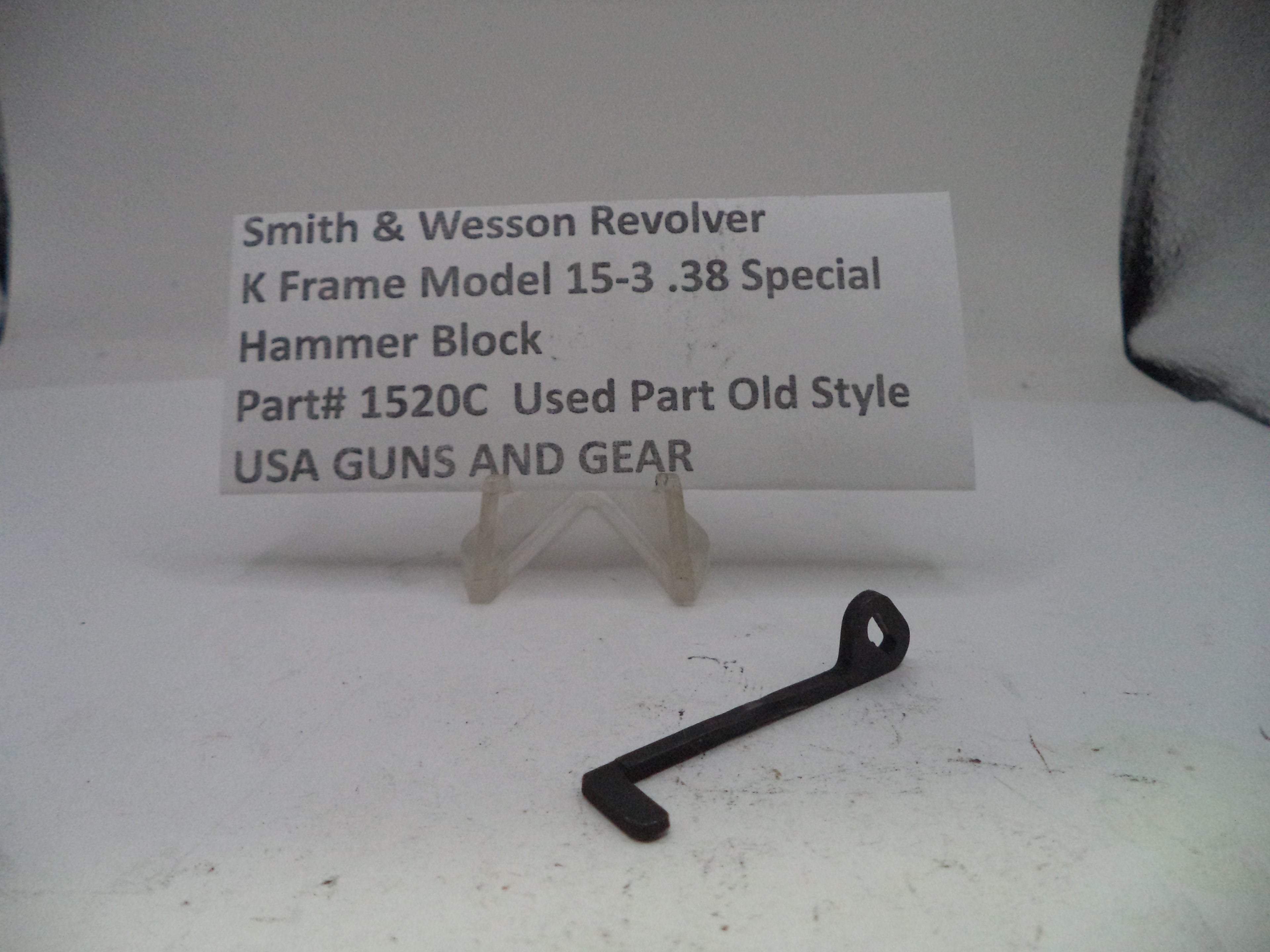Black revolver hammer block part on a white surface with a label reading 'Smith & Wesson Revolver K Frame Model 15-3 .38 Special'.