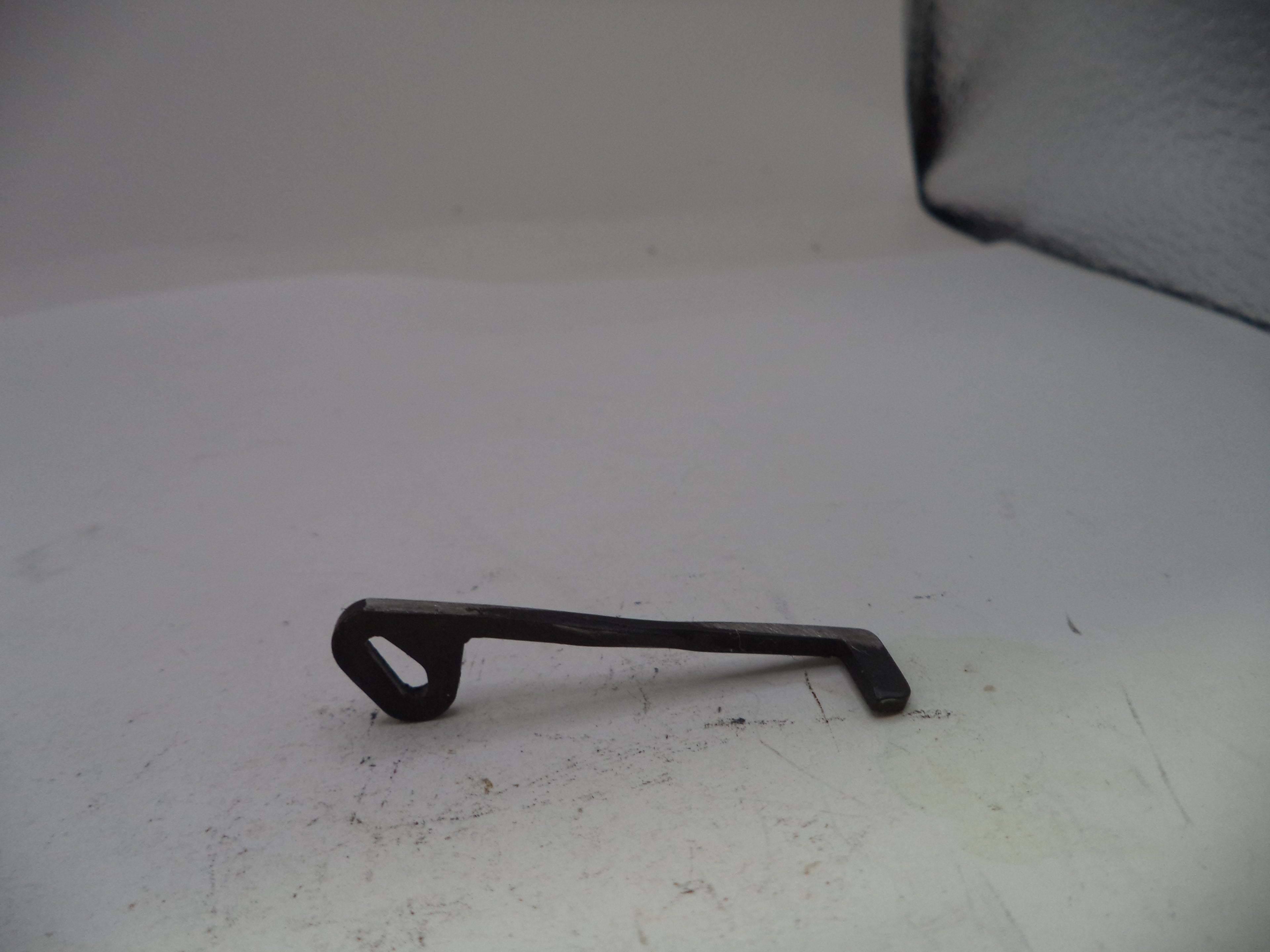 Black metal key-shaped object on a white surface