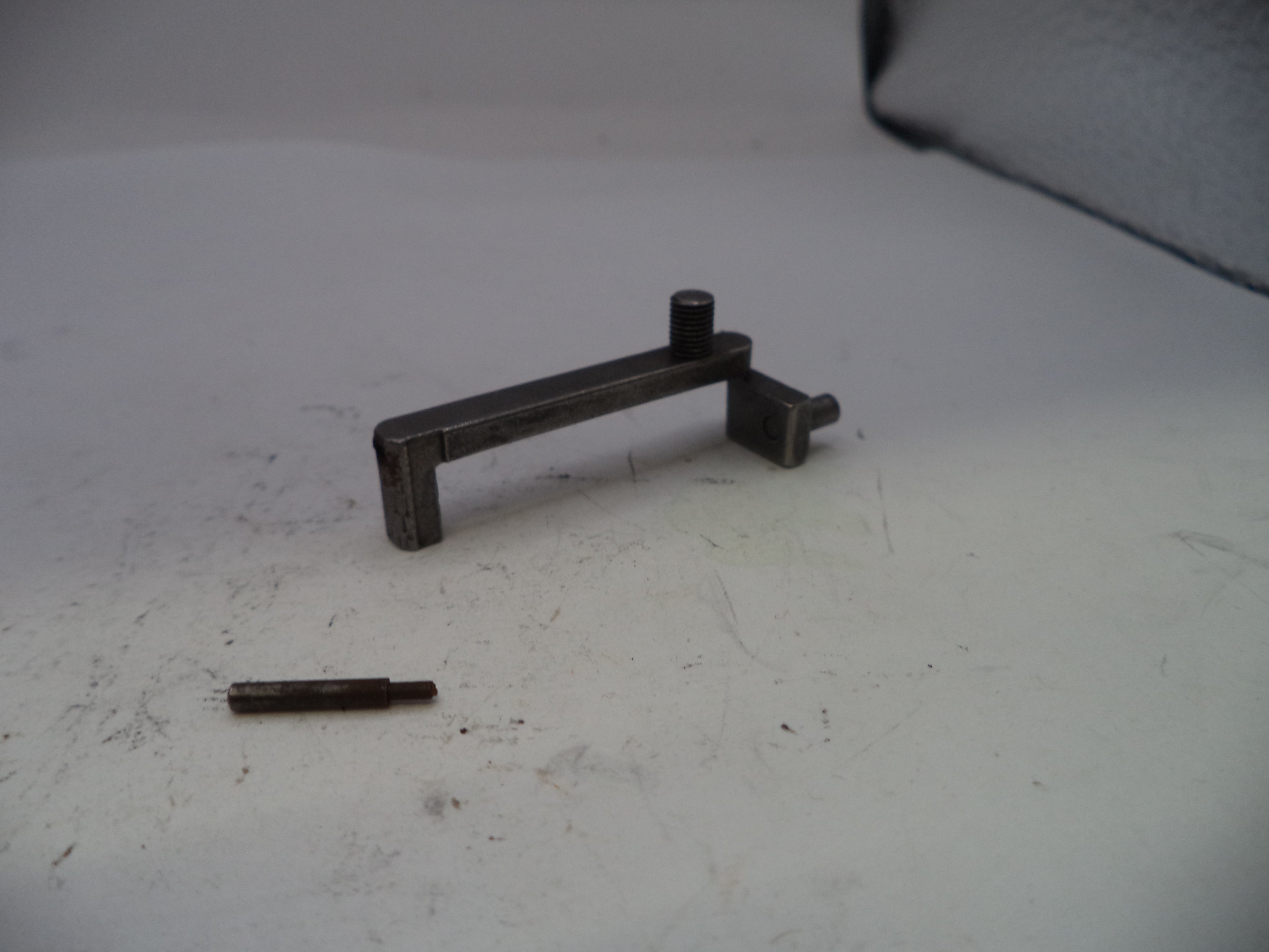 Metal lever and small cylindrical object on a white surface