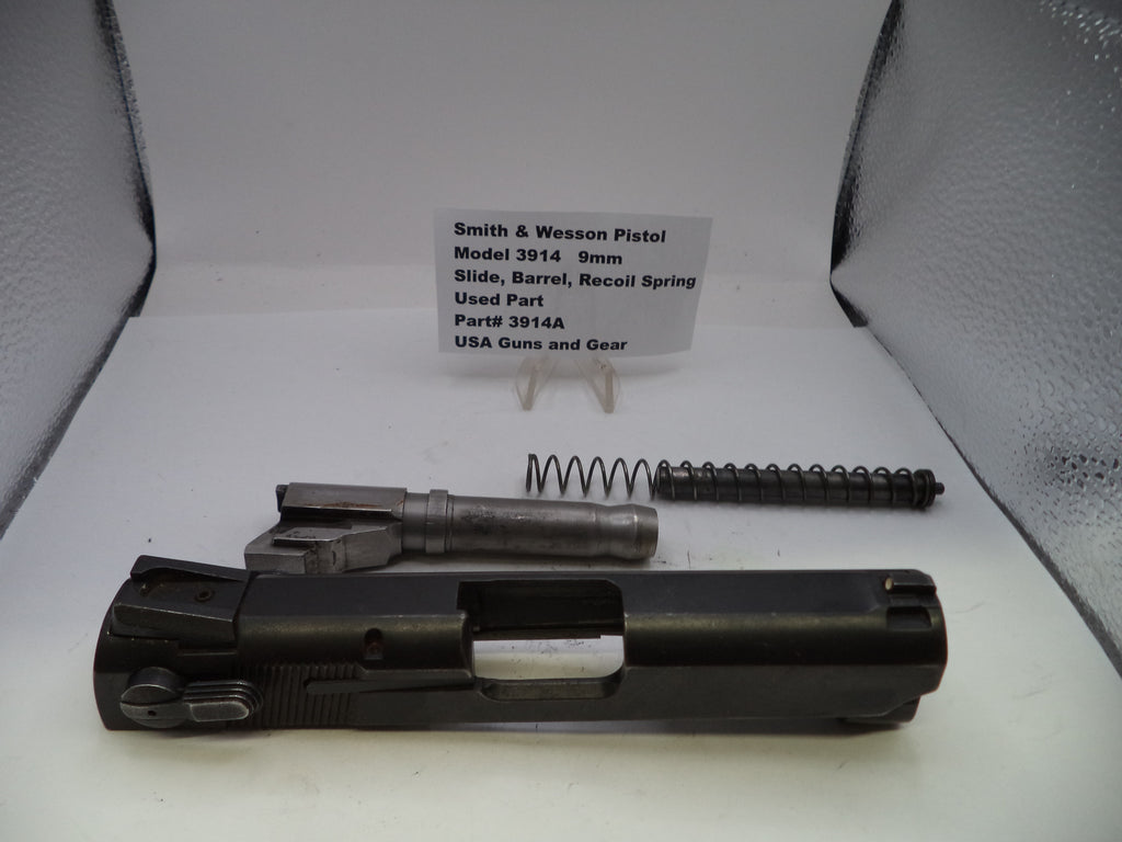 Smith & Wesson pistol parts including slide, barrel, and recoil spring on a white surface with a label.