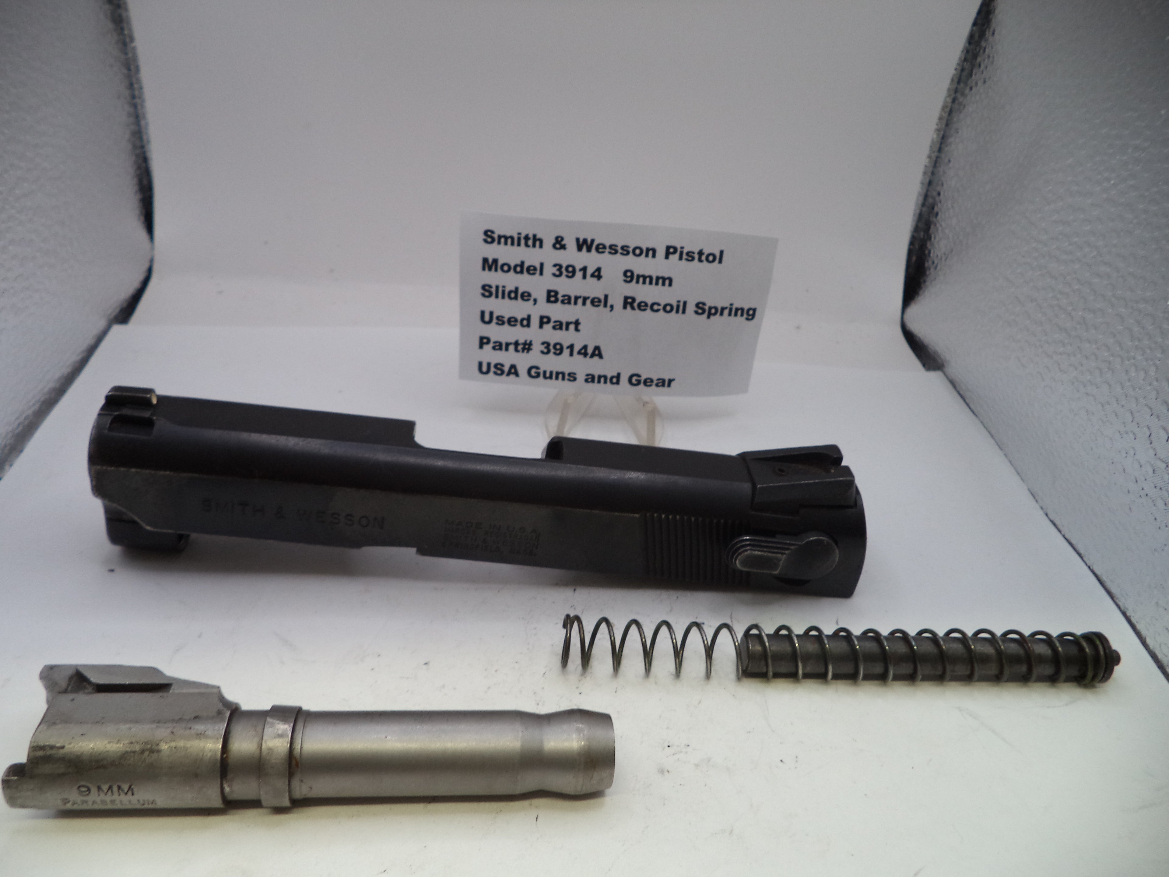 Smith & Wesson pistol parts including slide, barrel, and recoil spring on a white background with a label.