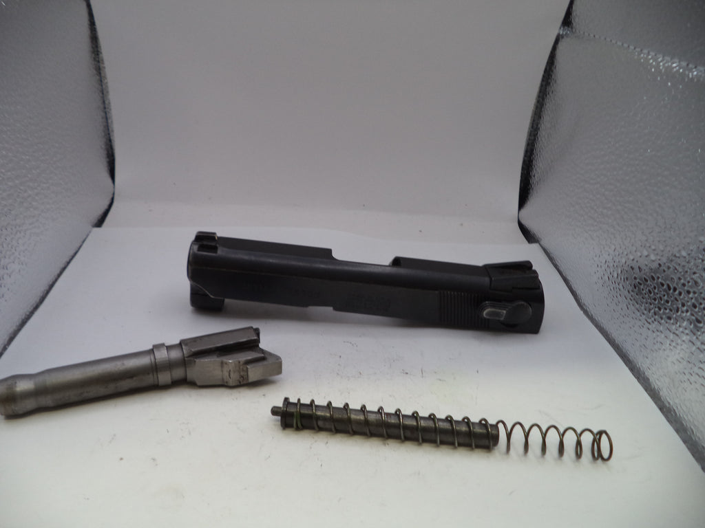 Gun components including a barrel, slide, and spring on a white surface with a gray background.