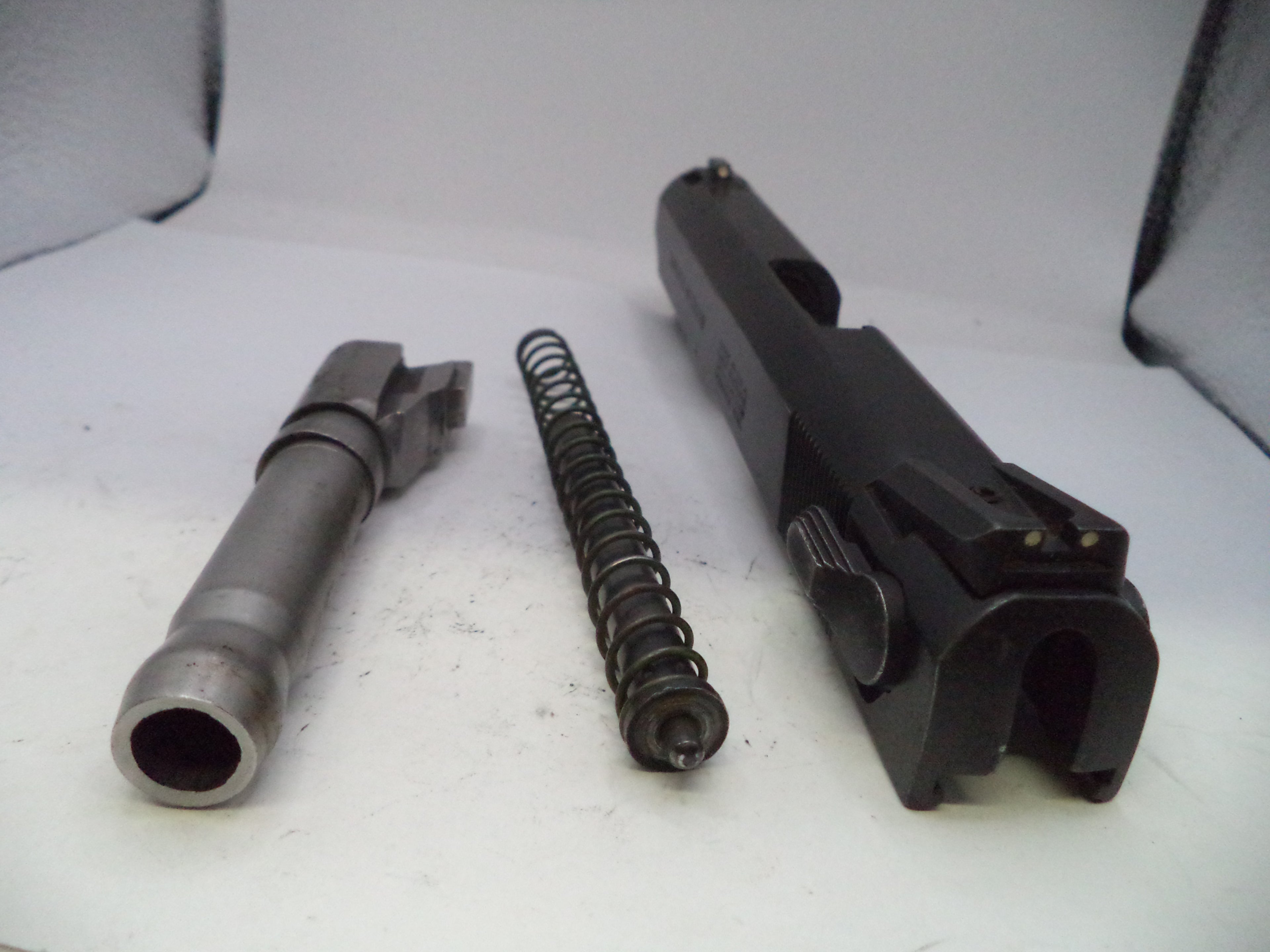 Gun components including a barrel, spring, and slide on a white background