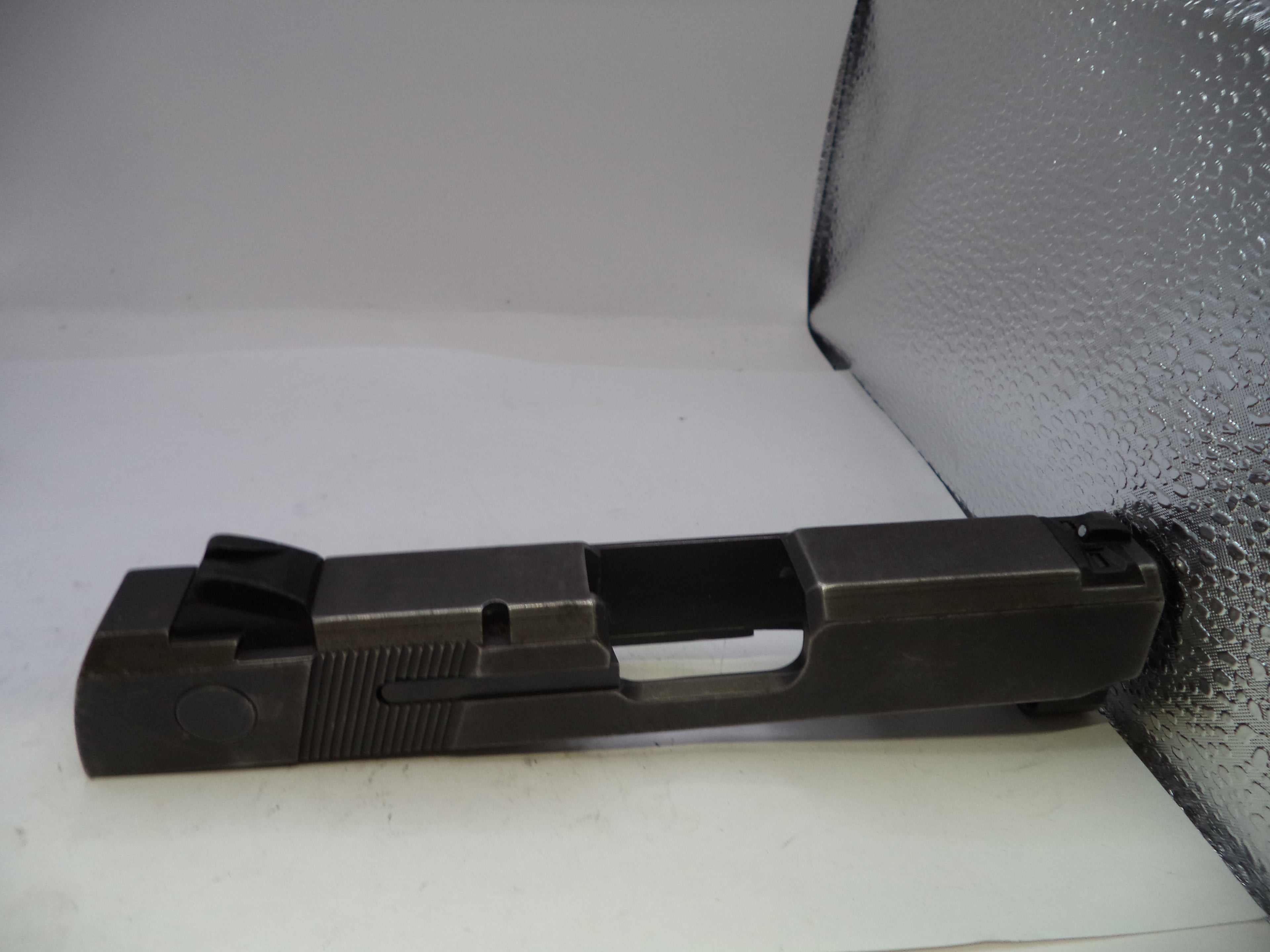 Black gun slide on a textured gray surface