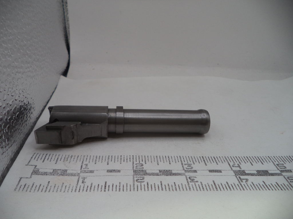 Metal gun barrel on a white surface with measurement scale