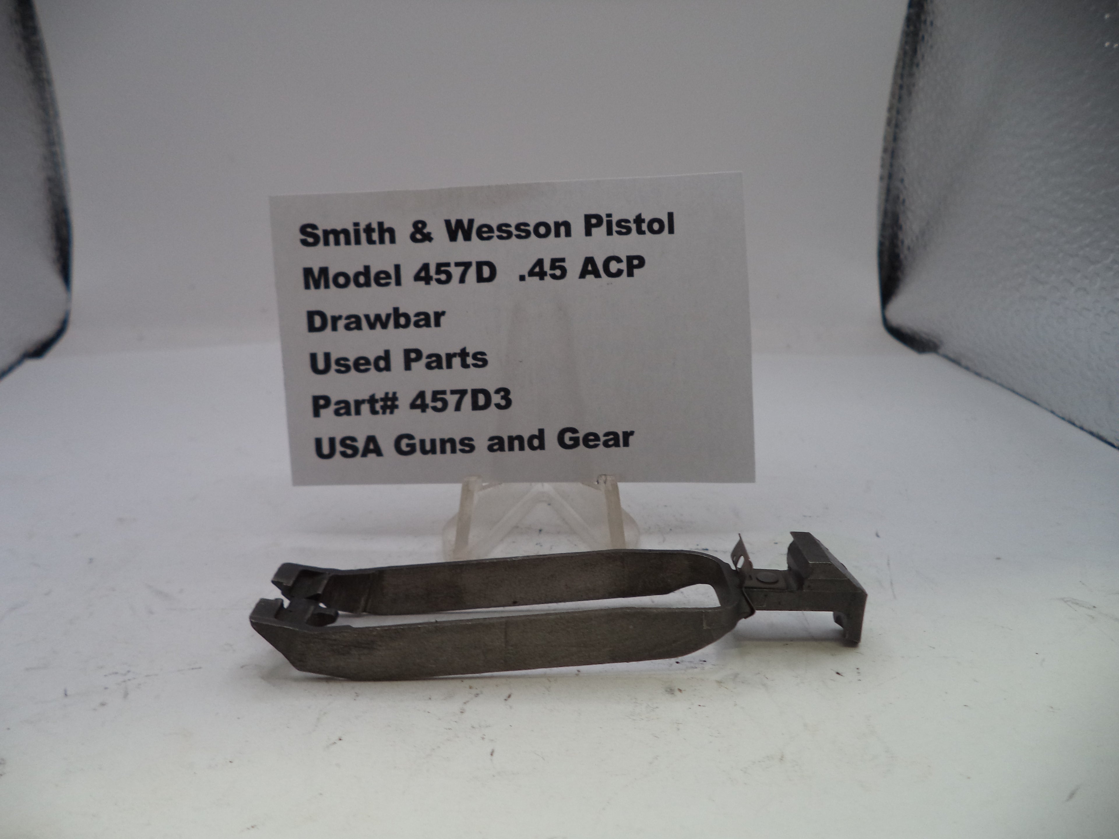 Smith & Wesson pistol drawbar part with a label on a white background