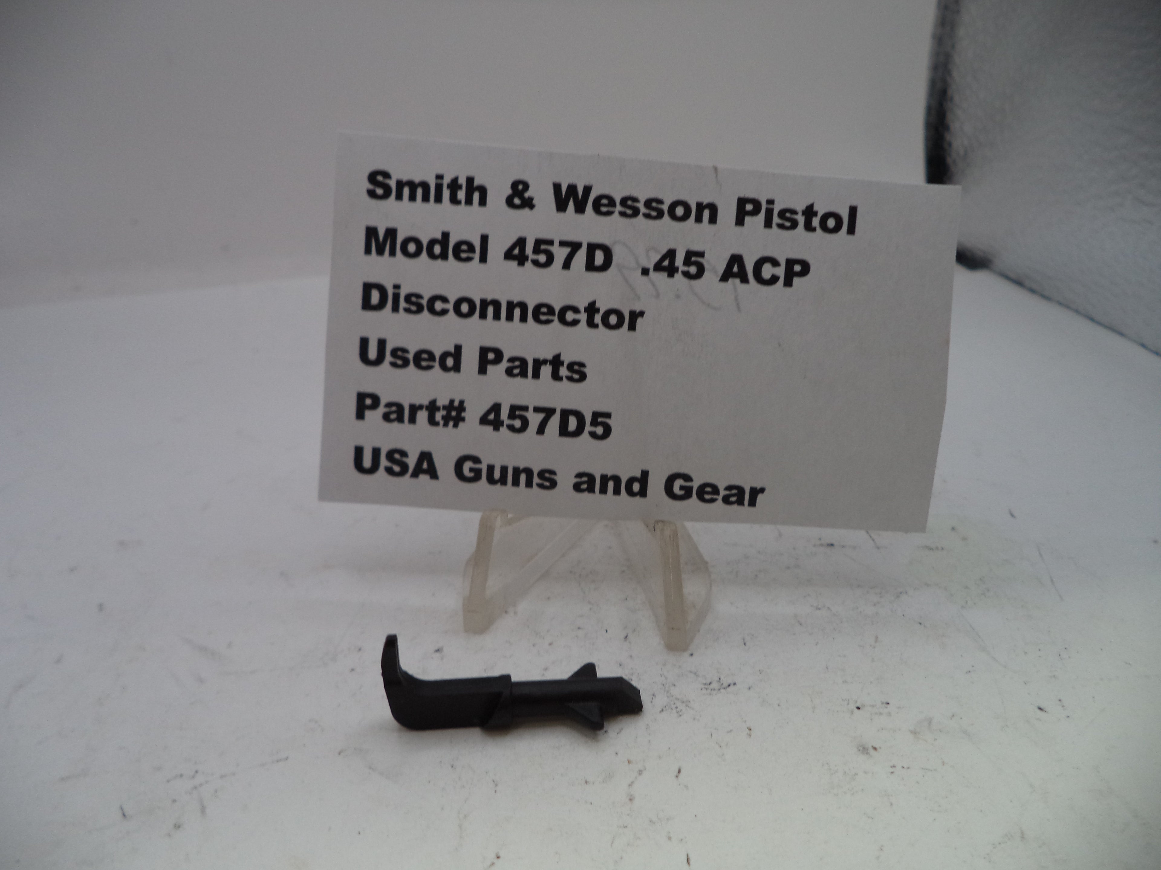 Smith & Wesson pistol disconnector part with a label on a white background