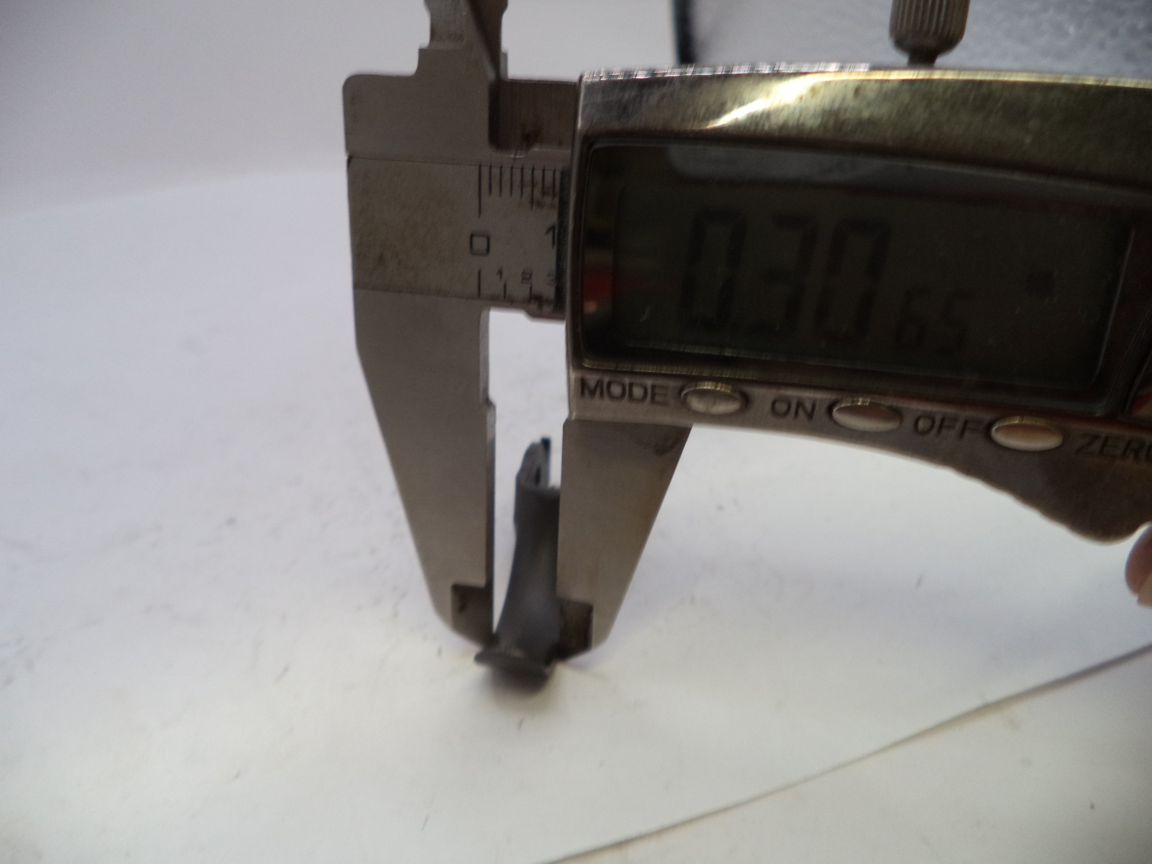Digital caliper measuring a small object on a white background