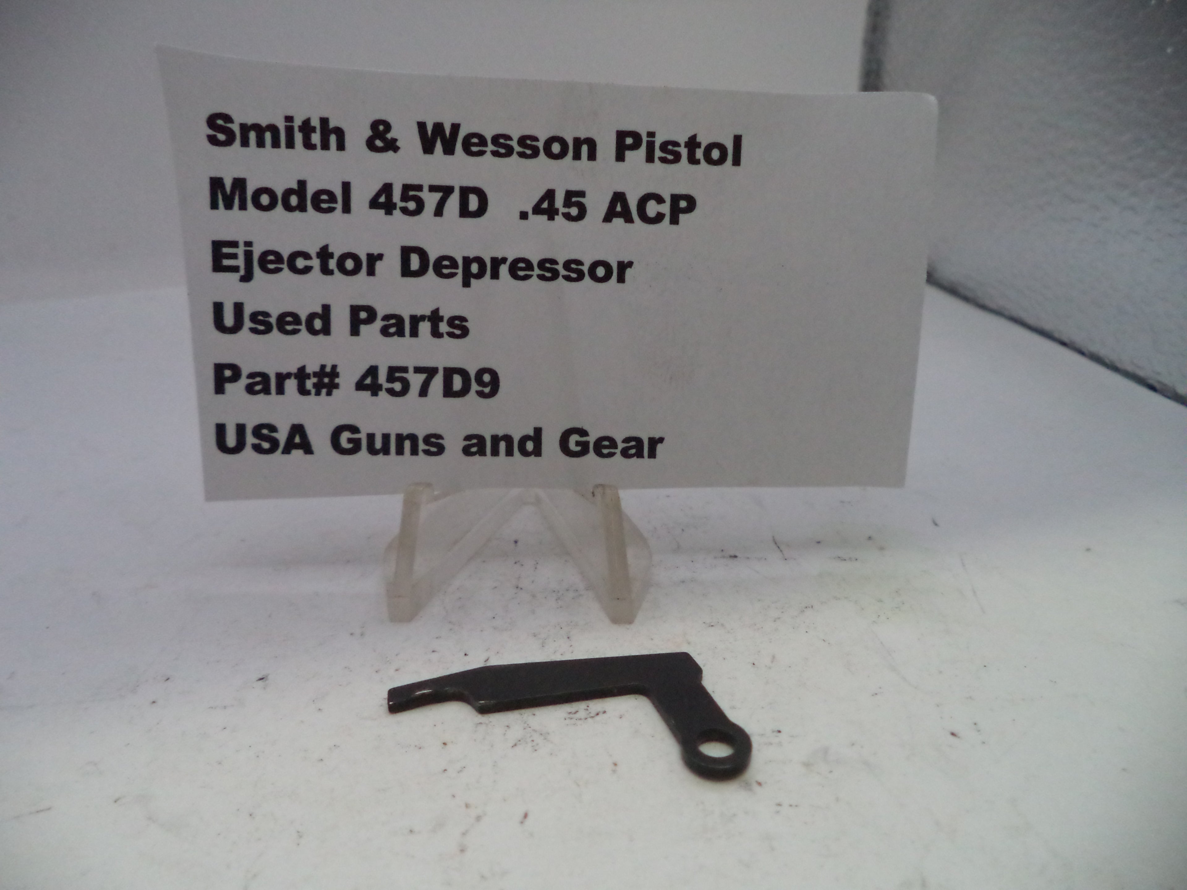 Black ejector depressor for Smith & Wesson Pistol Model 457D .45 ACP on a white background with a label.