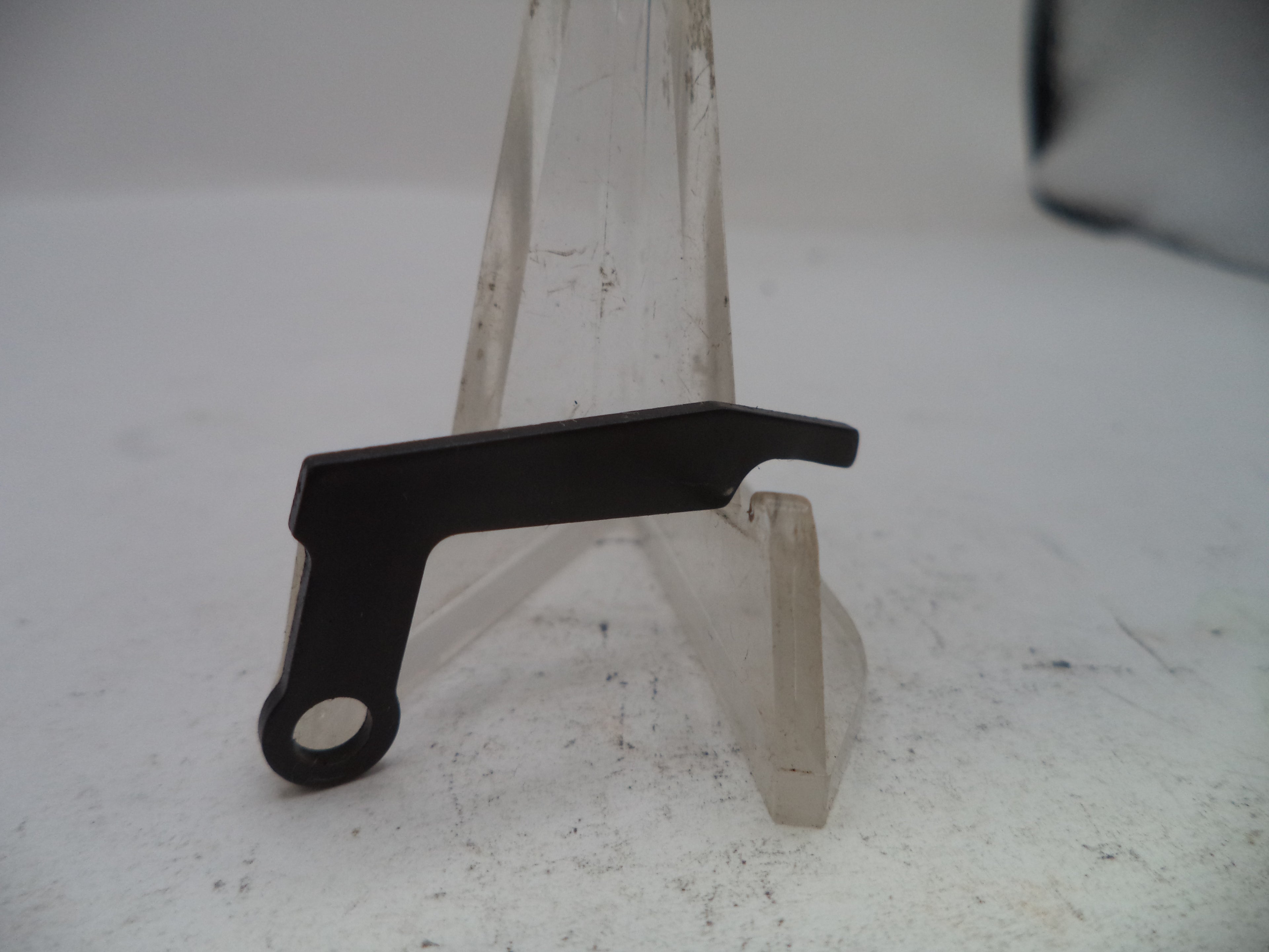Metal bracket with a black component on a white surface
