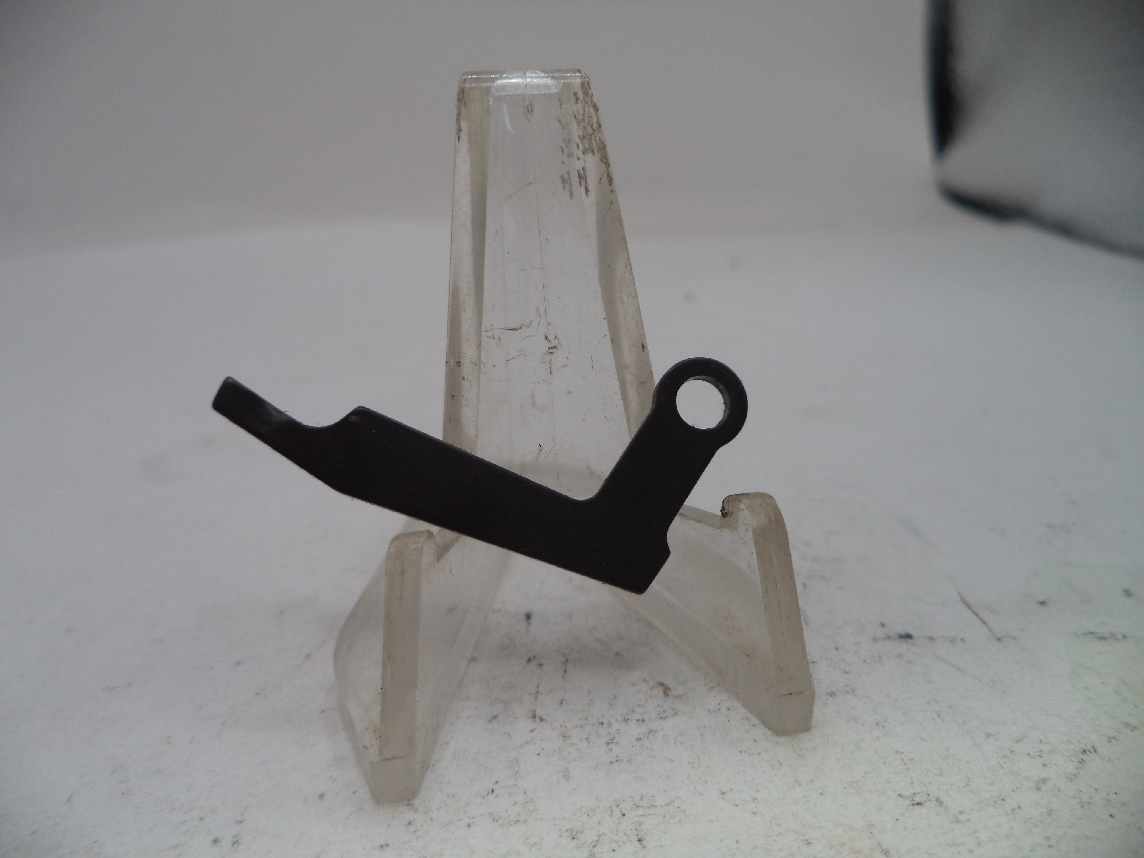 Black metal bracket on a clear plastic stand against a white background