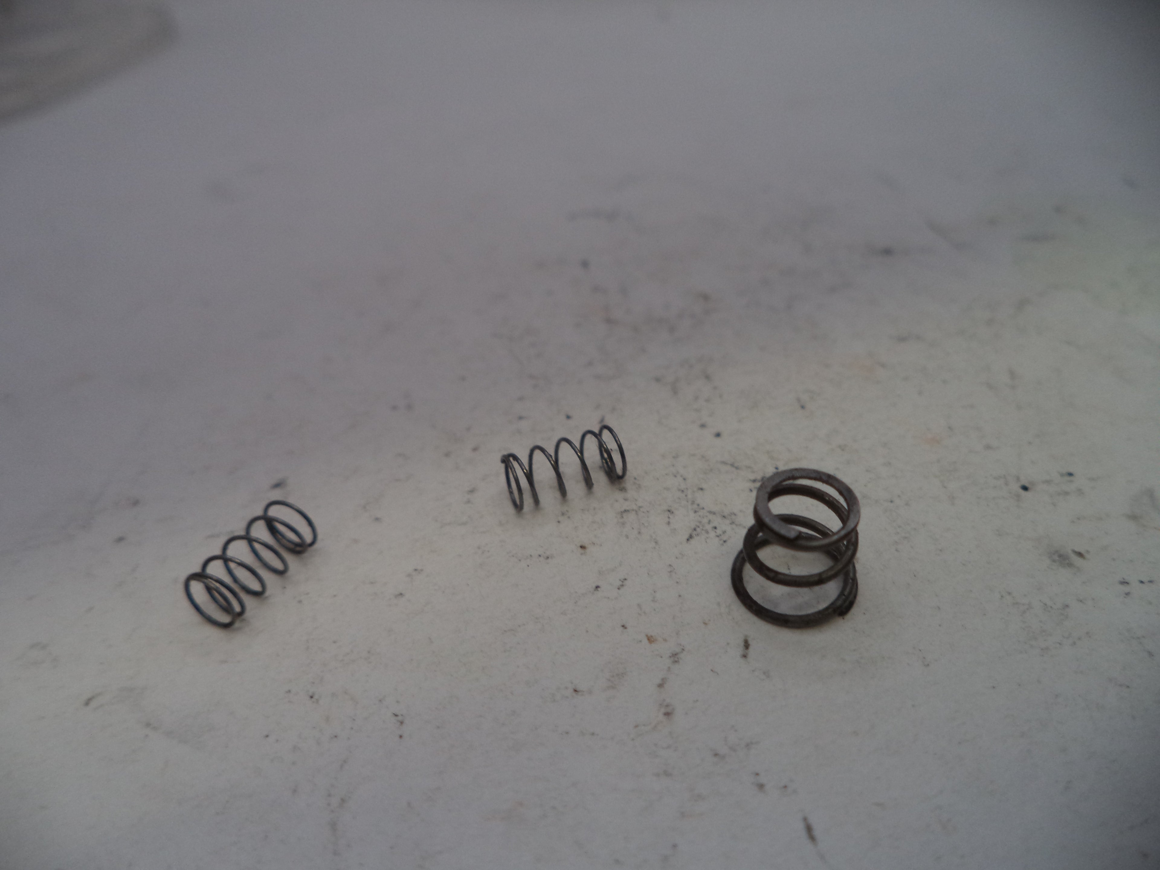 Three metal springs on a white surface