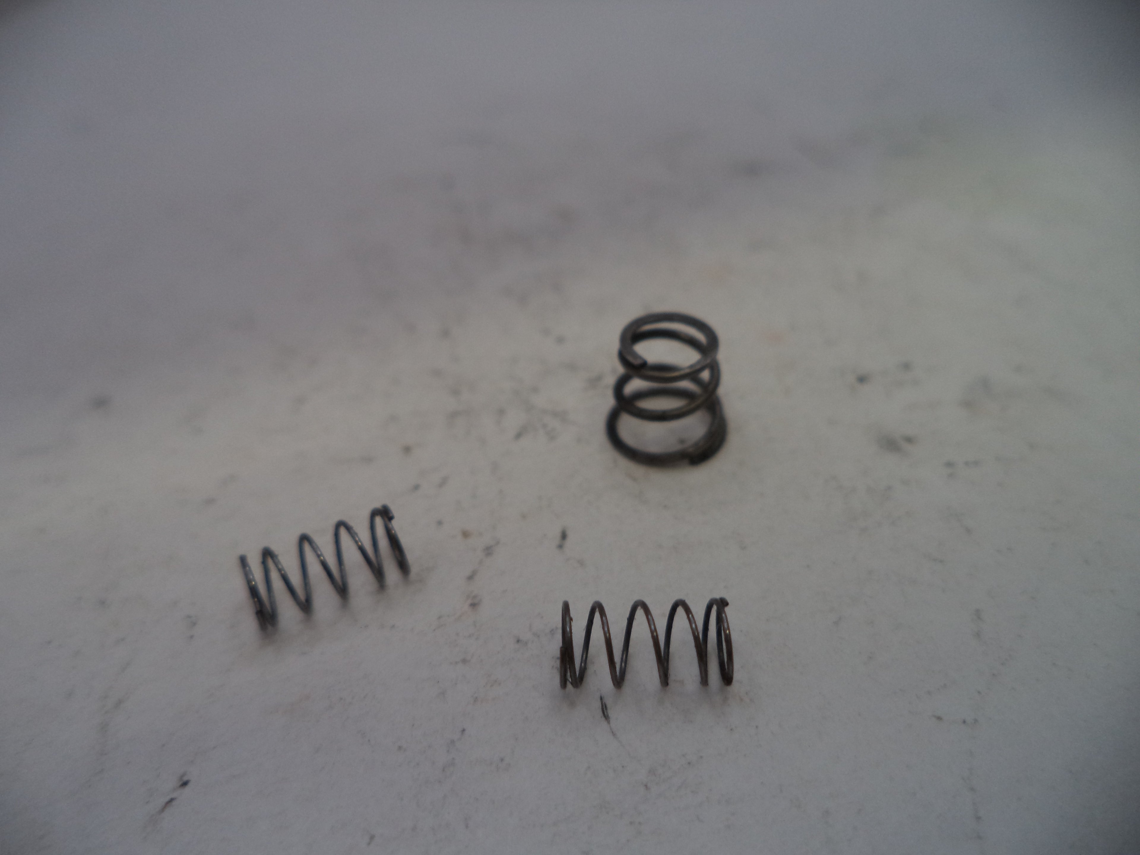 Three metal springs on a textured white surface