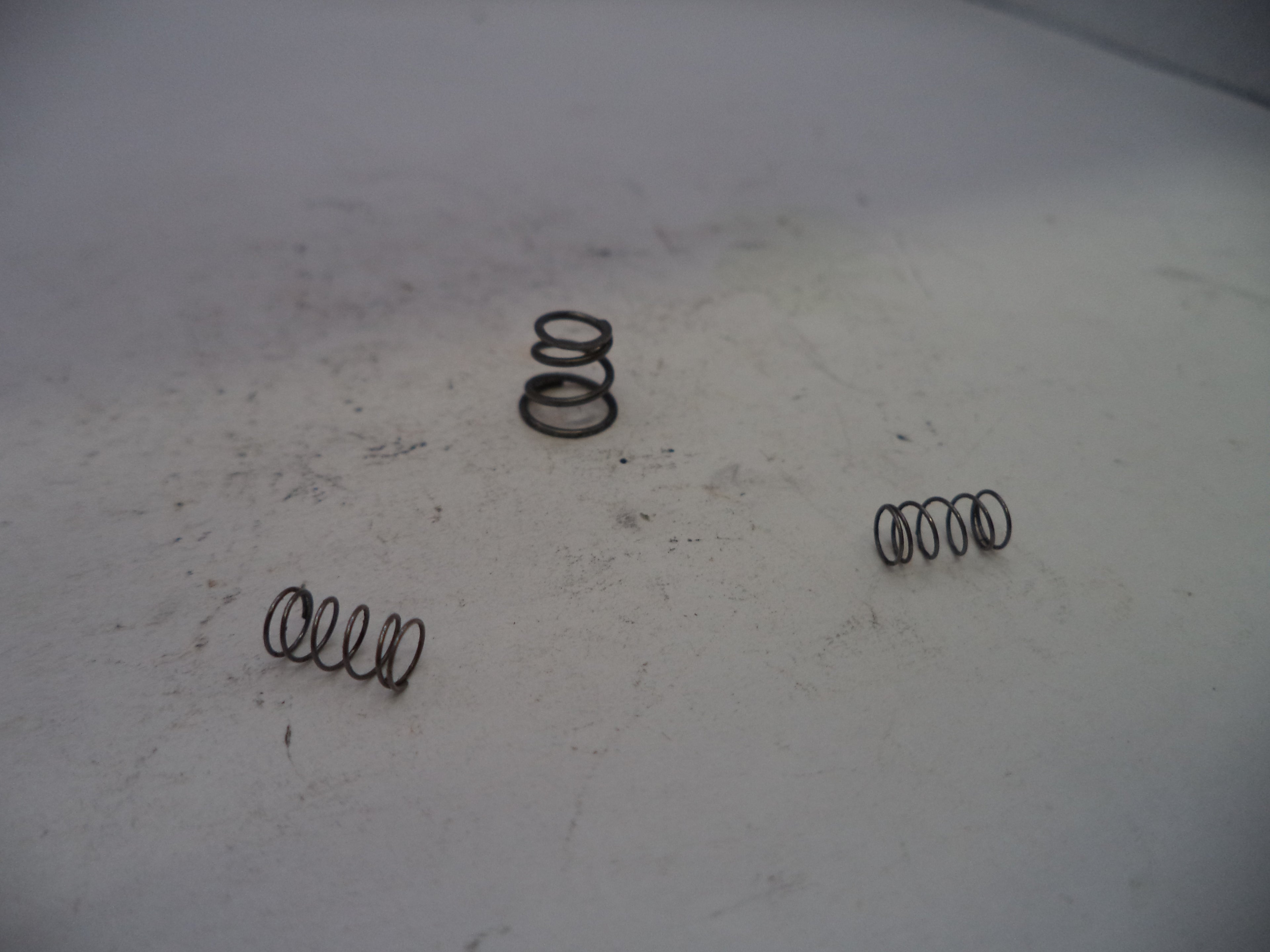 Three metal springs on a worn white surface