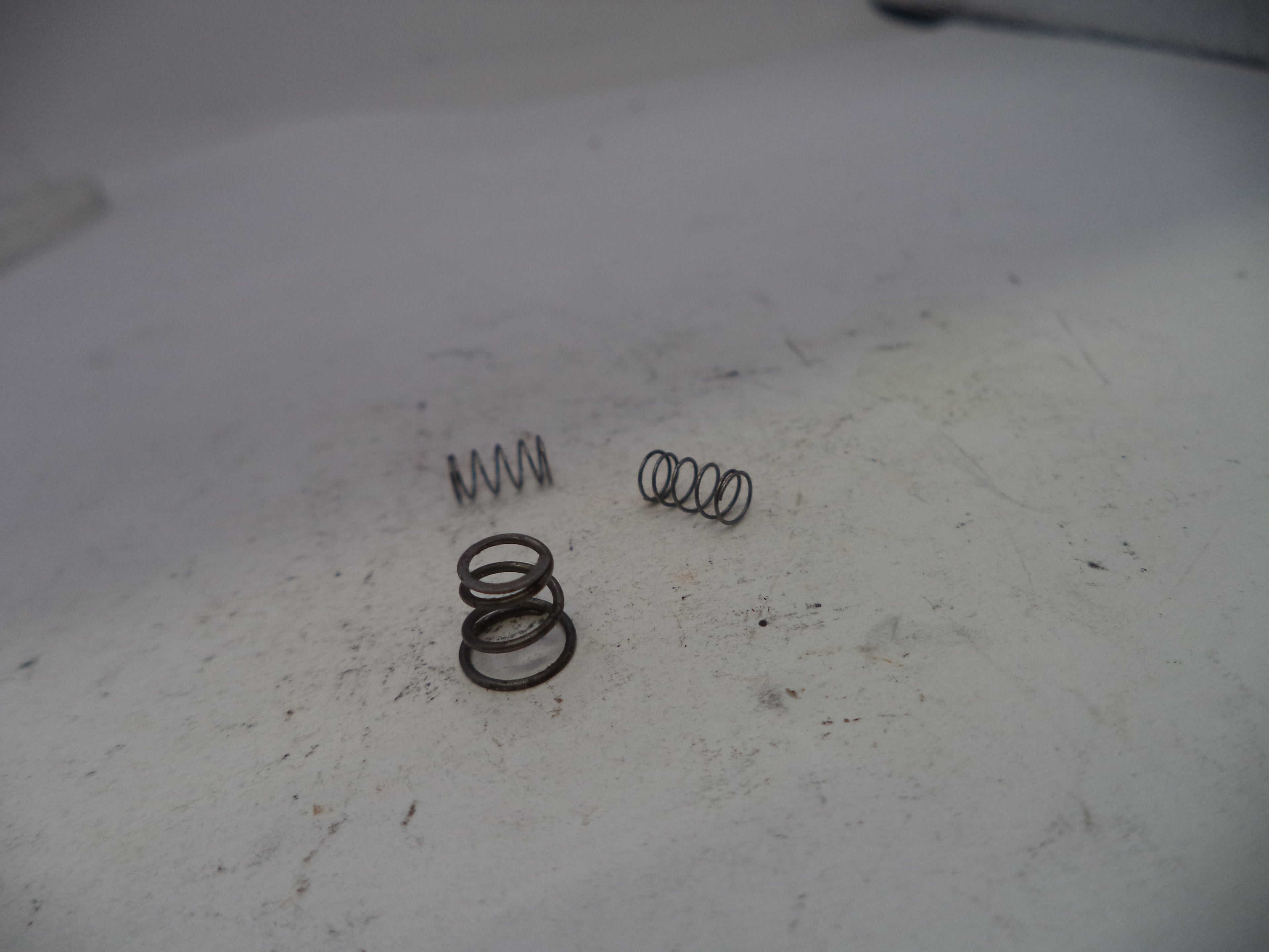 Three metal springs on a worn white surface