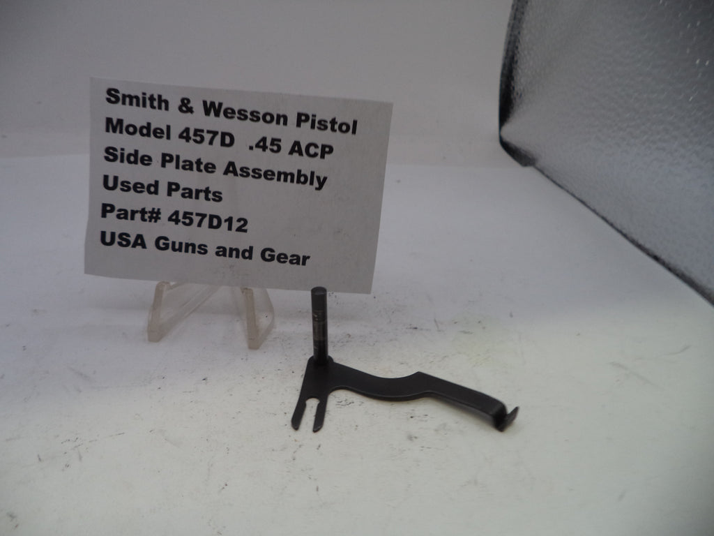 Black Smith & Wesson pistol side plate assembly on a white background with a label.