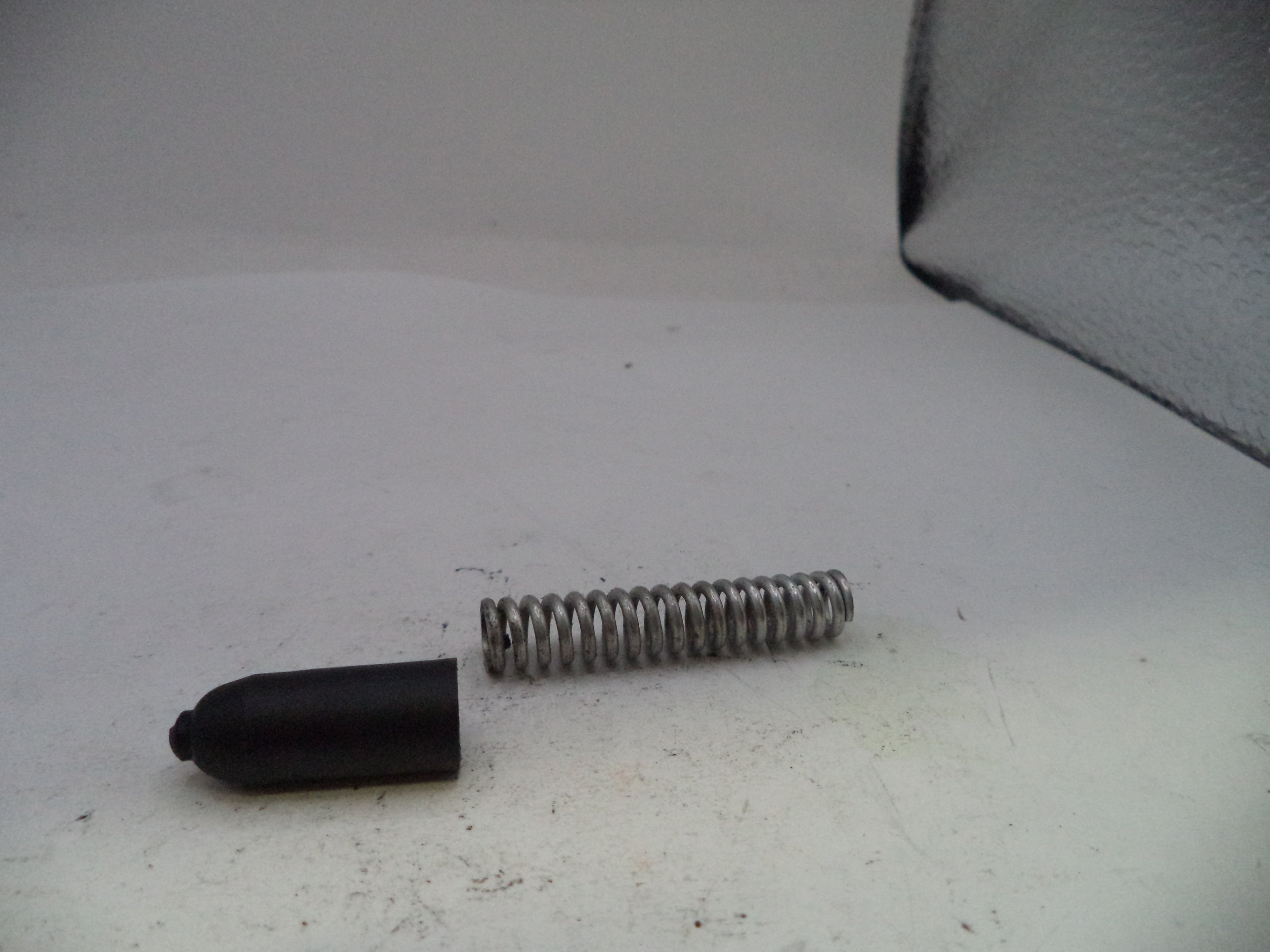 Black rubber tip and metal spring on a white surface