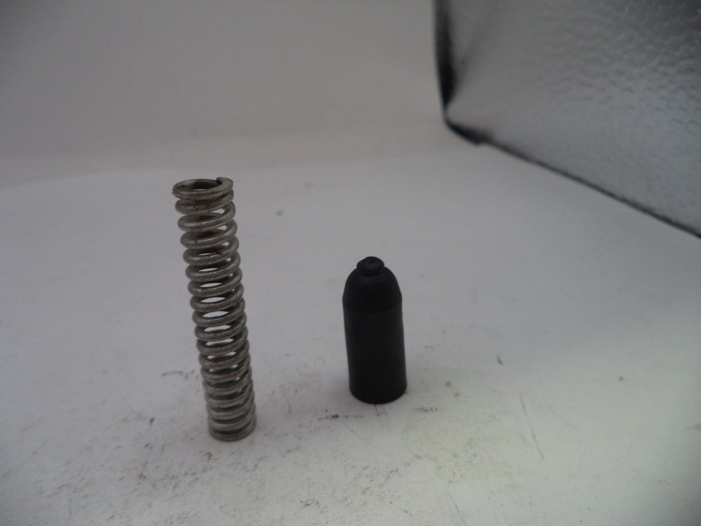 Metal spring and black cylindrical object on a white surface