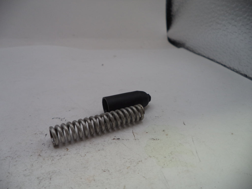 Metal spring and black cylindrical object on a white surface