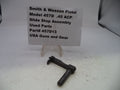 Smith & Wesson pistol slide stop assembly on a white surface with a label.