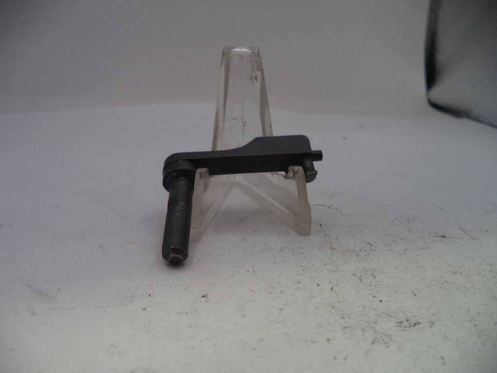 Small black metal component on a clear stand against a light gray background