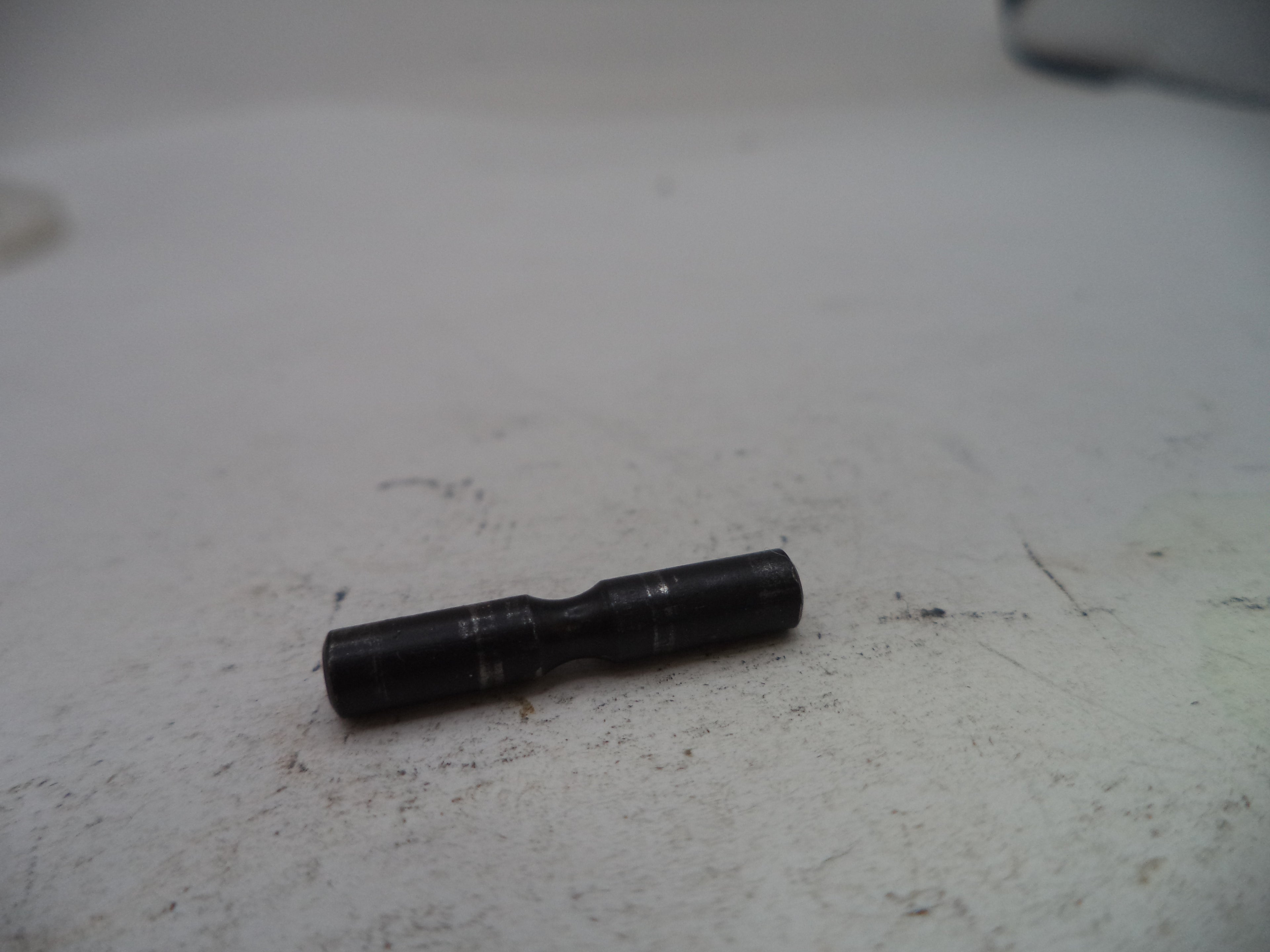 Black cylindrical object on a textured white surface