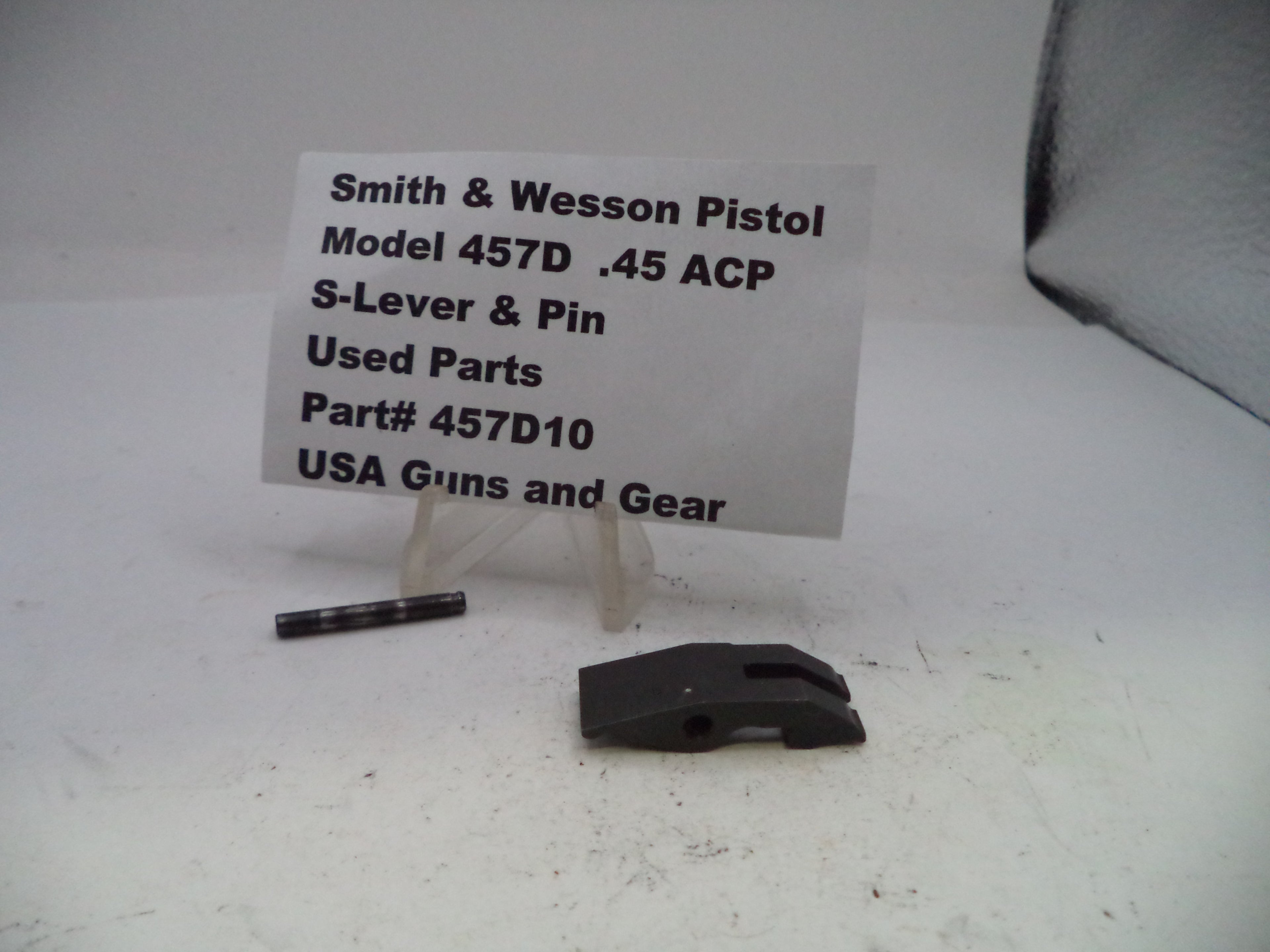 Smith & Wesson pistol parts on a white surface with a label.
