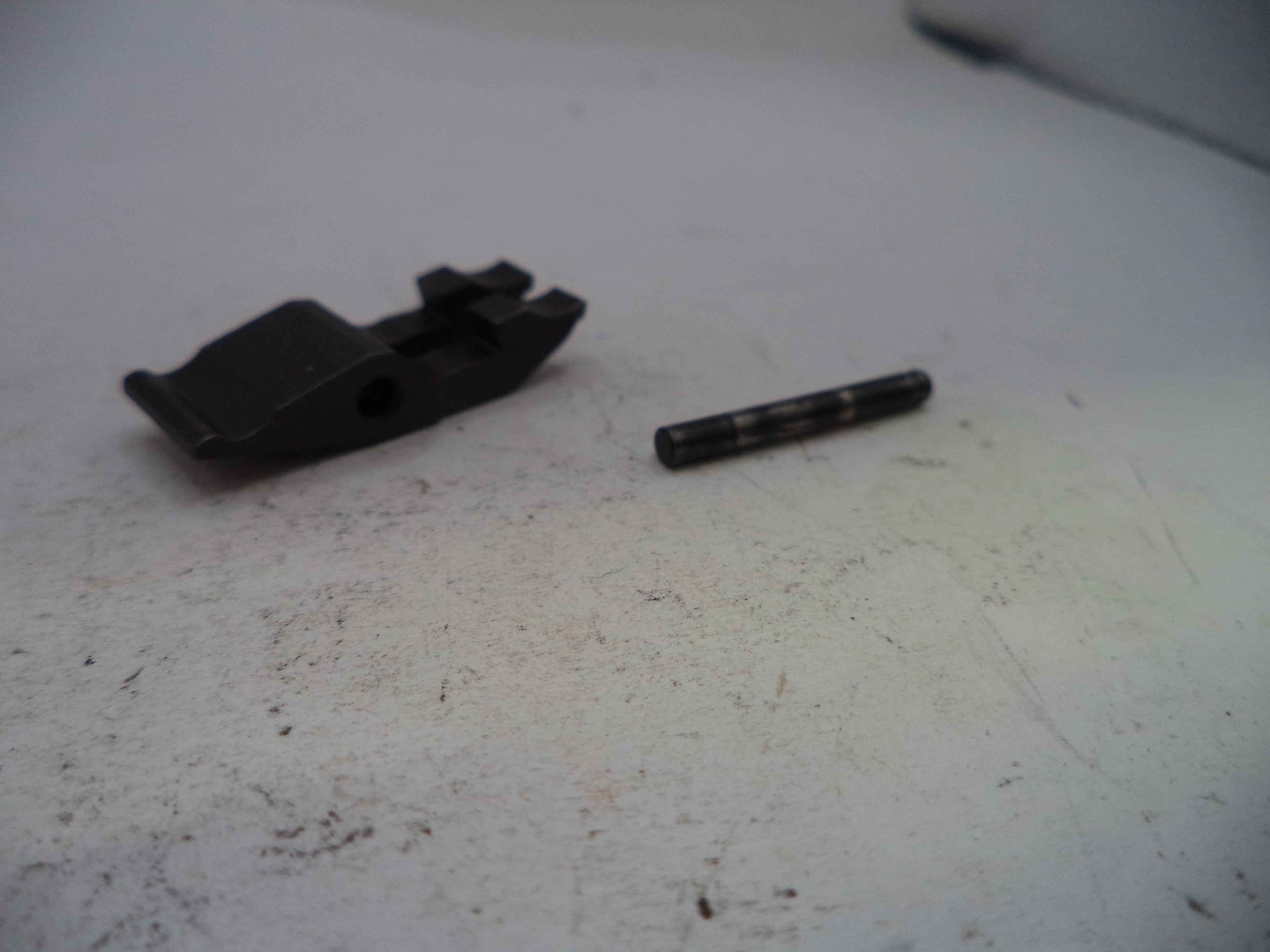 Two black mechanical parts on a worn white surface