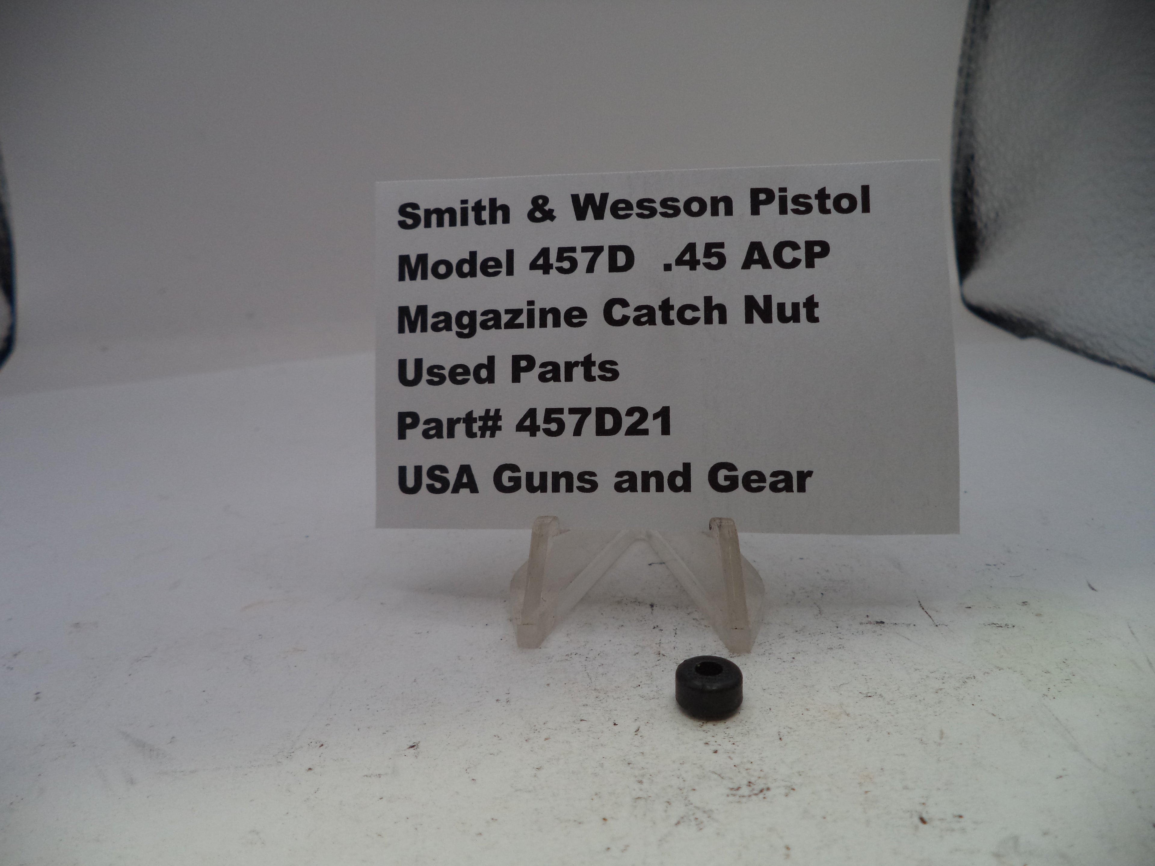 Black magazine catch nut with a label on a white background