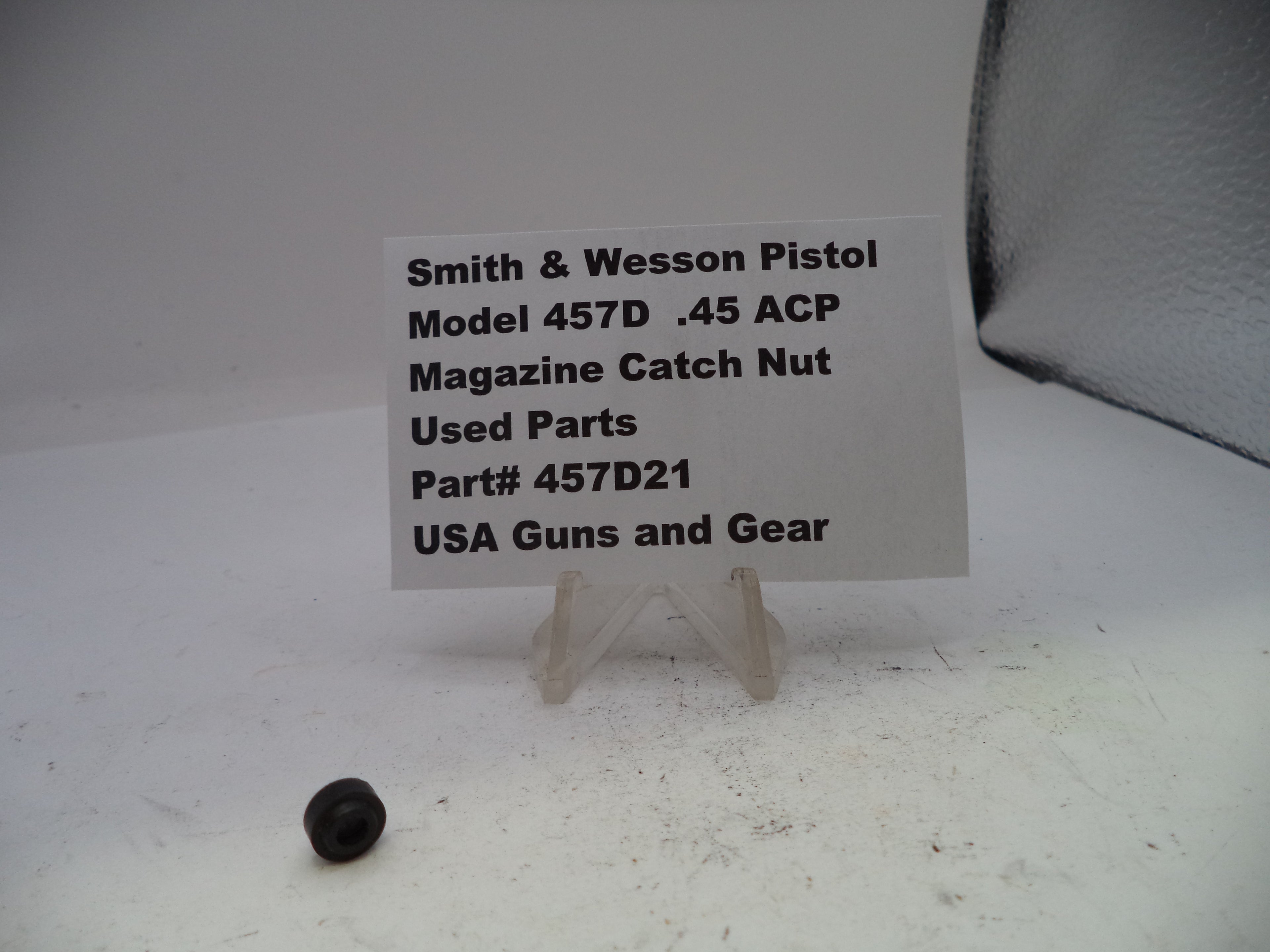 Black magazine catch nut with a label on a white background