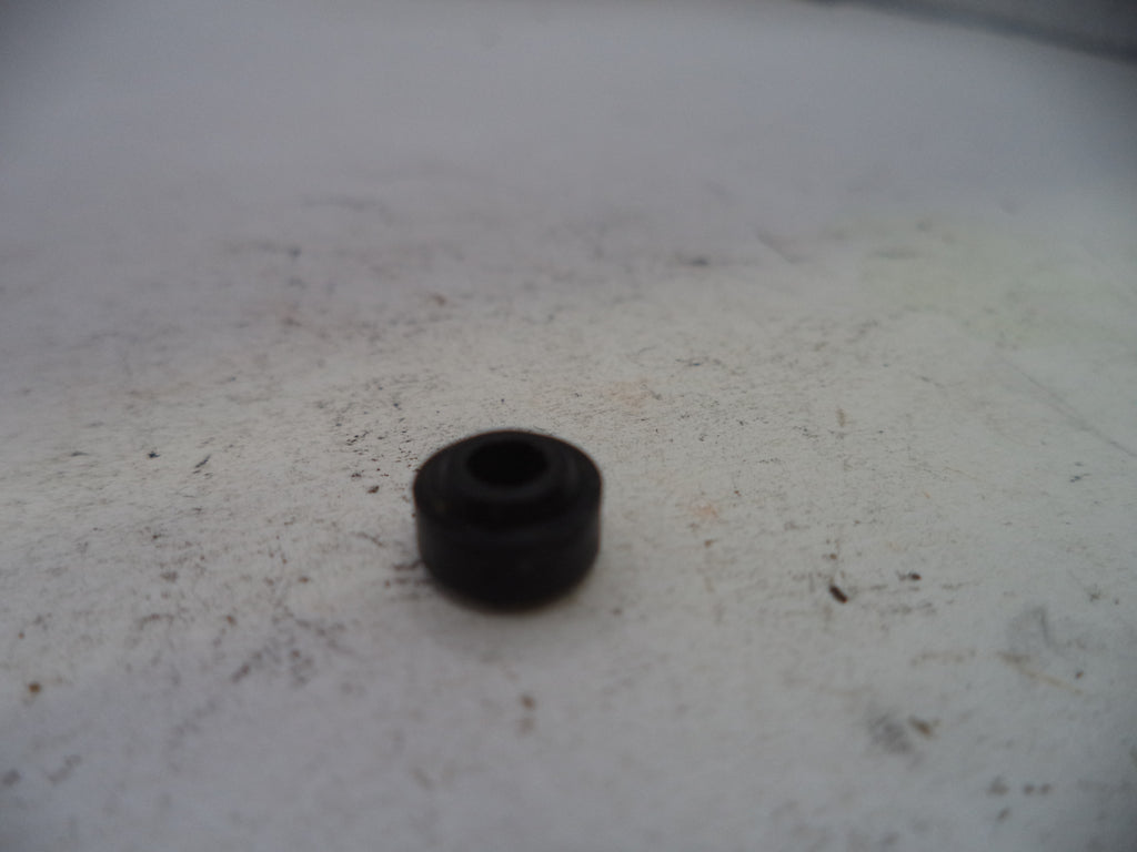 Small black rubber bushing on a white surface with visible dirt.
