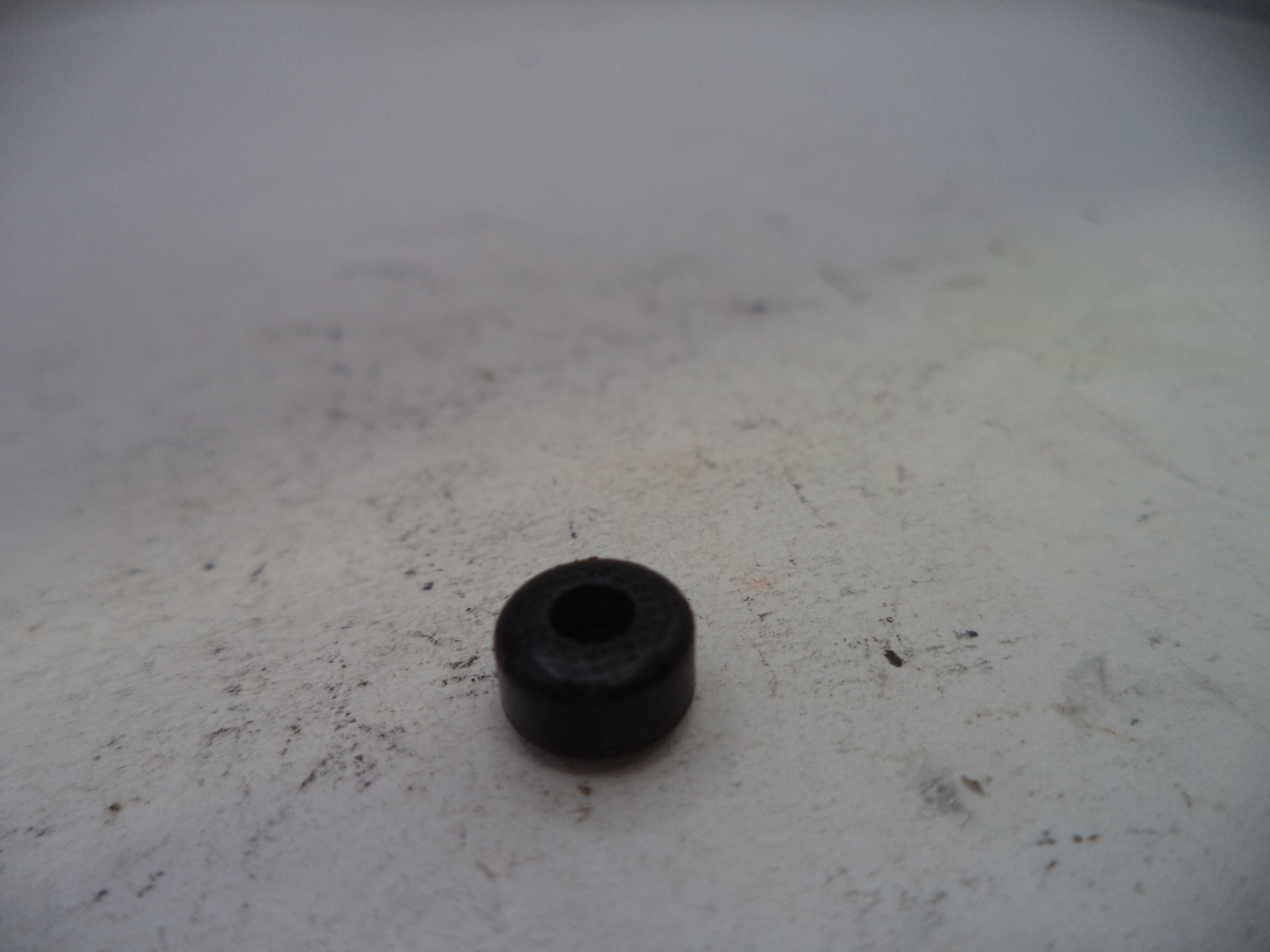 Black rubber bushing on a textured white surface