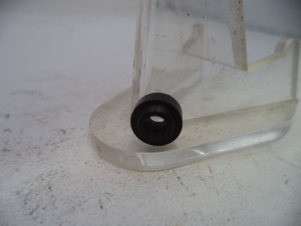 Clear plastic stand with a black rubber bushing on a white surface