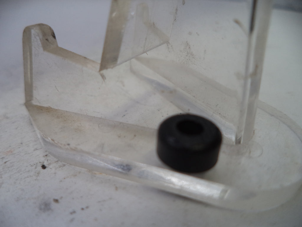 Clear plastic component with a black rubber bushing on a white background