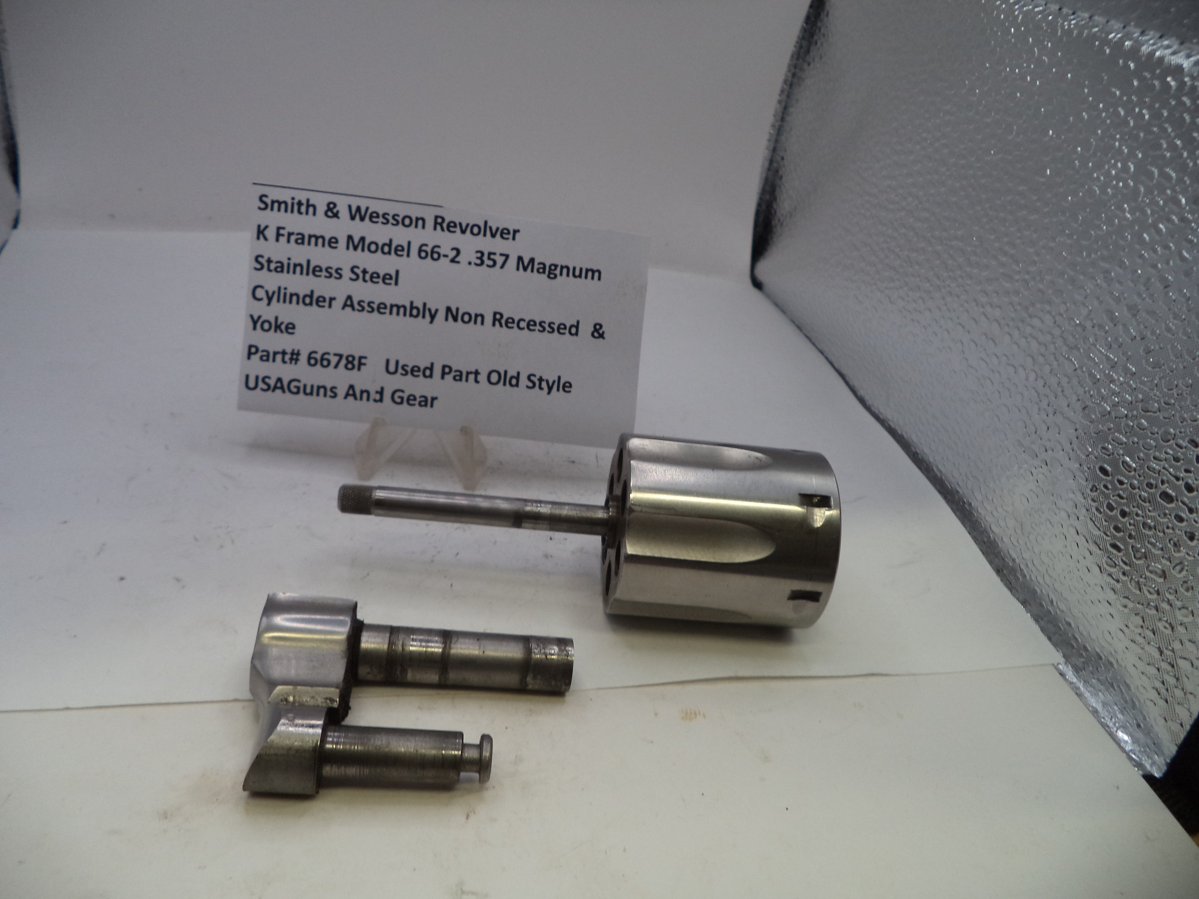 Smith & Wesson revolver cylinder assembly on a white surface with a label.