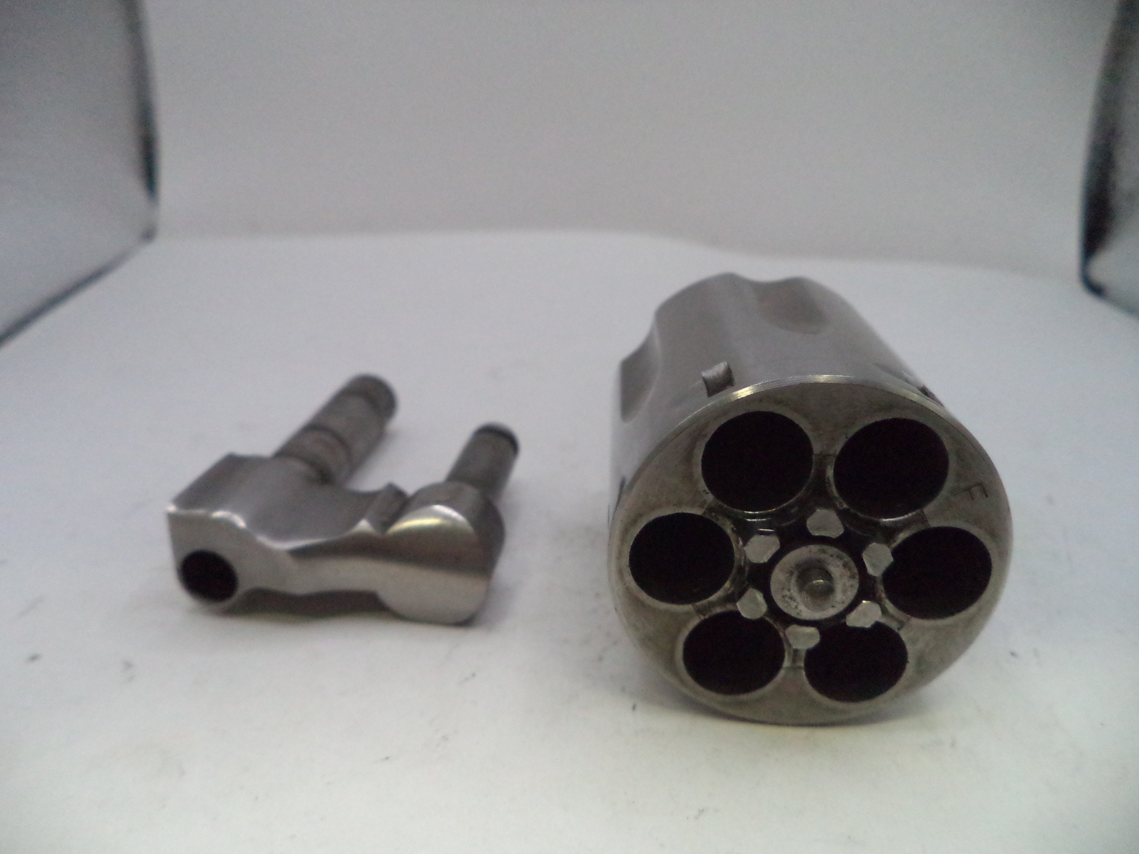 Metallic revolver barrel and cylinder on a white surface