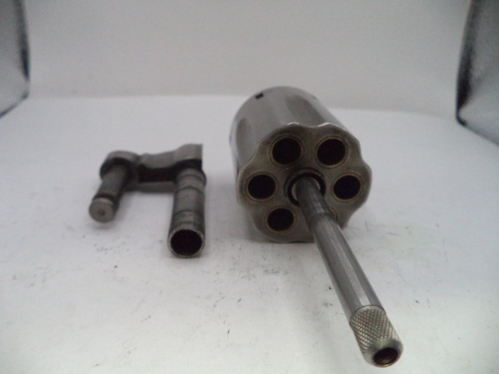 Metallic cylindrical object with multiple chambers on a white surface