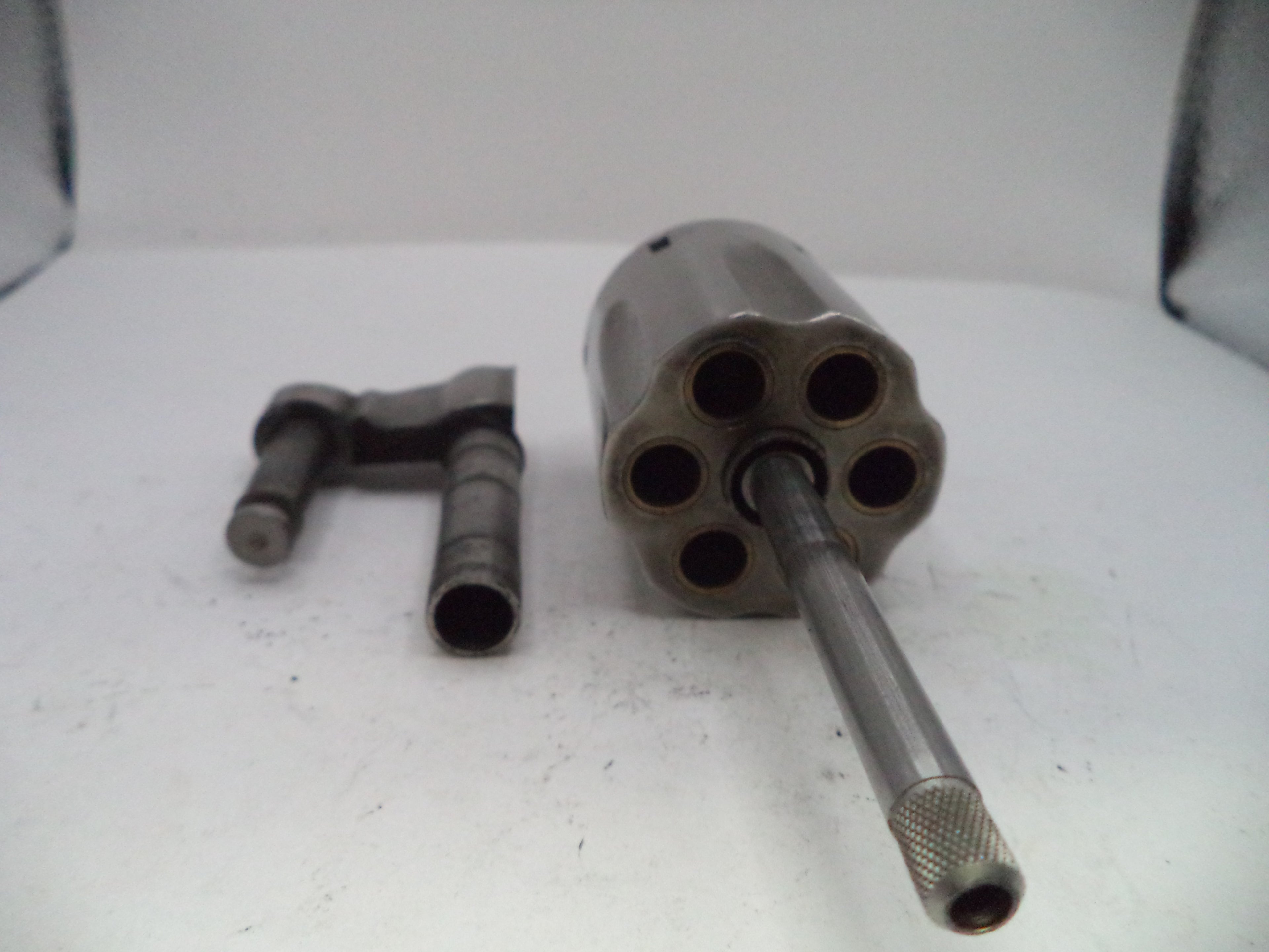 Metallic cylindrical object with multiple chambers on a white surface