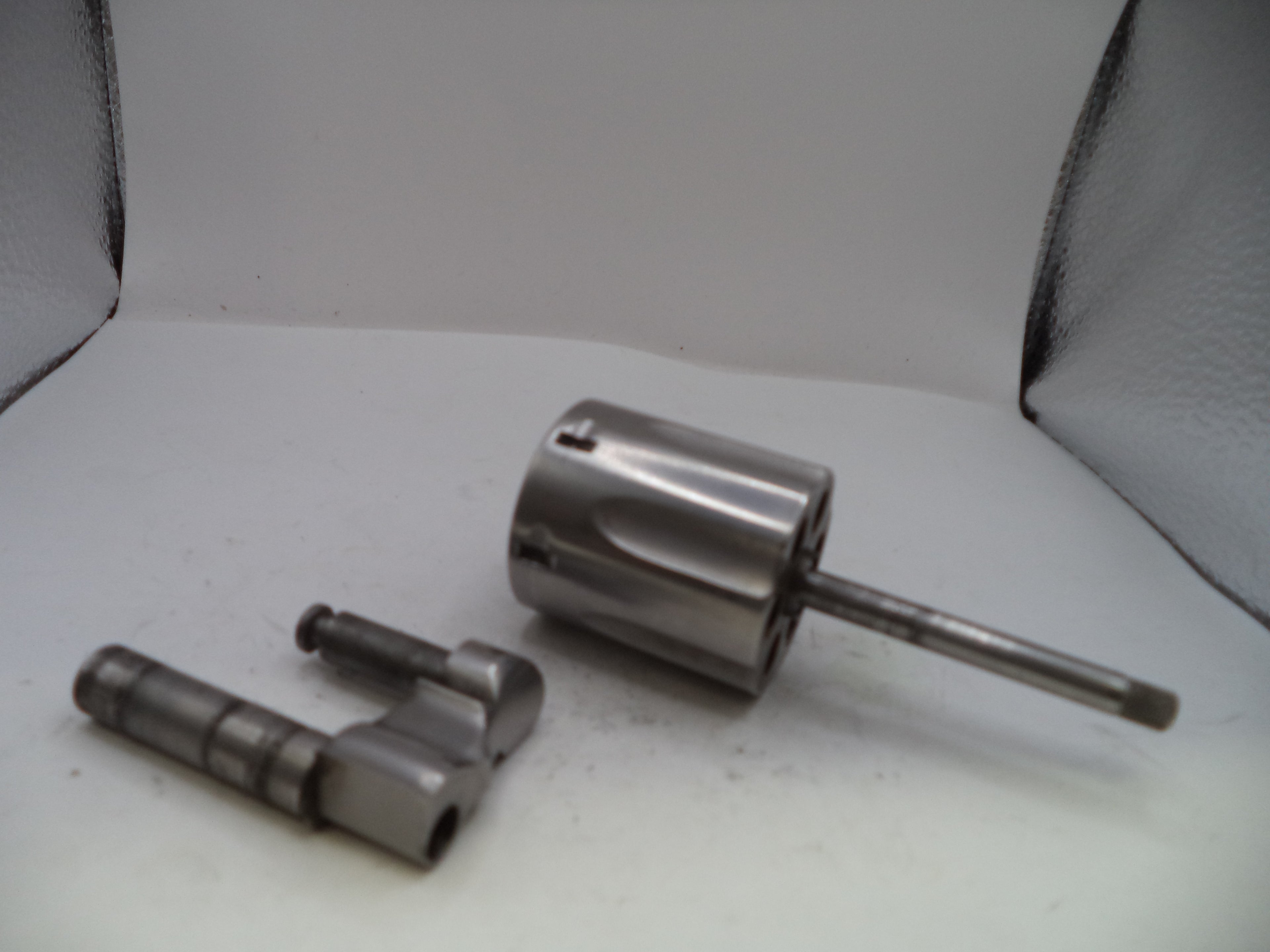 Two metal cylindrical components on a white surface with a gray background