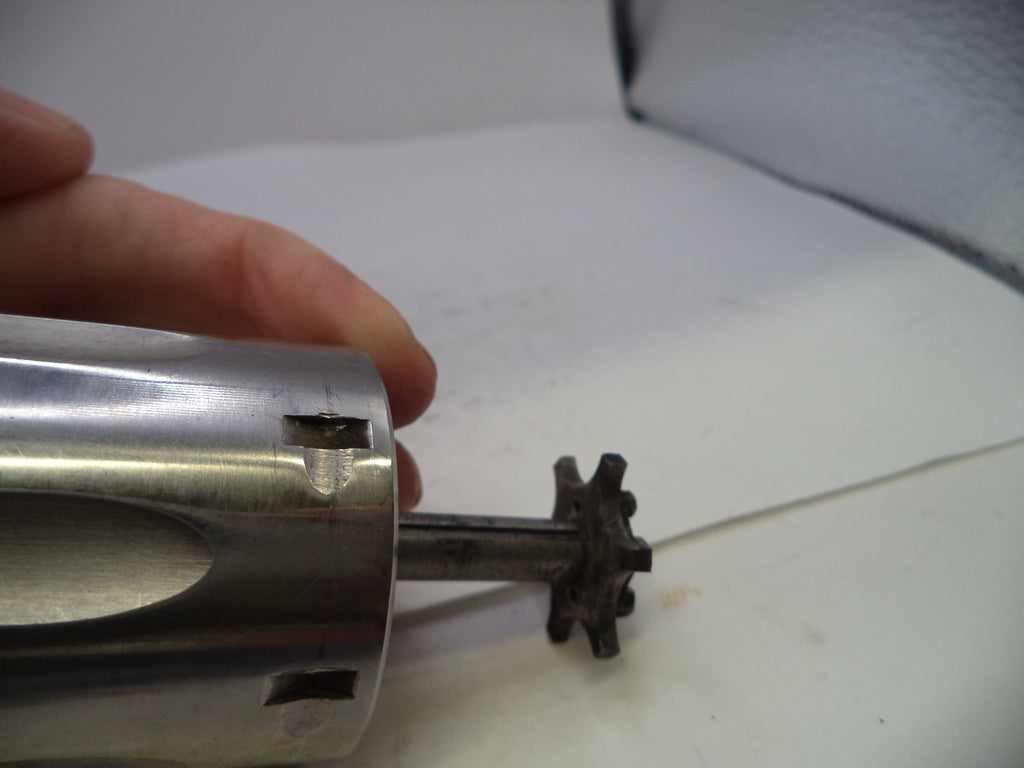 Metallic cylindrical object with a gear-like component on a white surface.