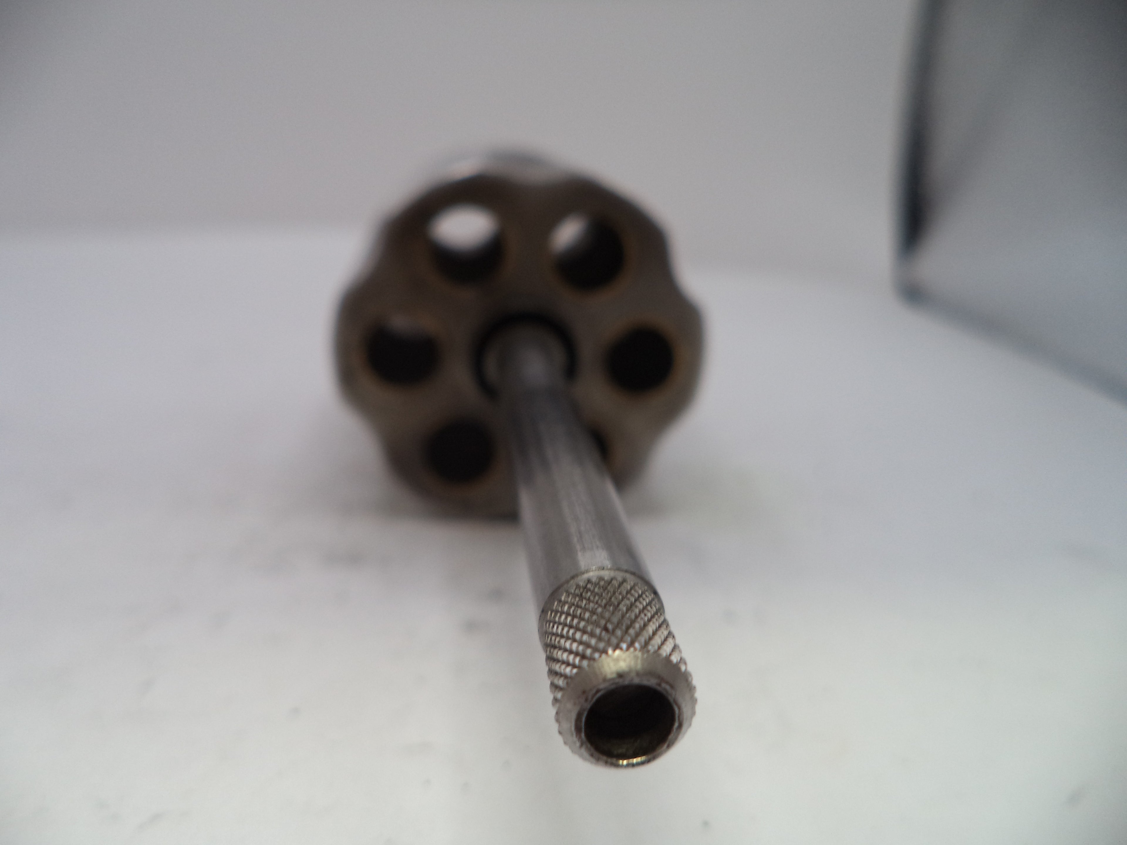 Close-up of a metal cylindrical object with a textured end on a white surface