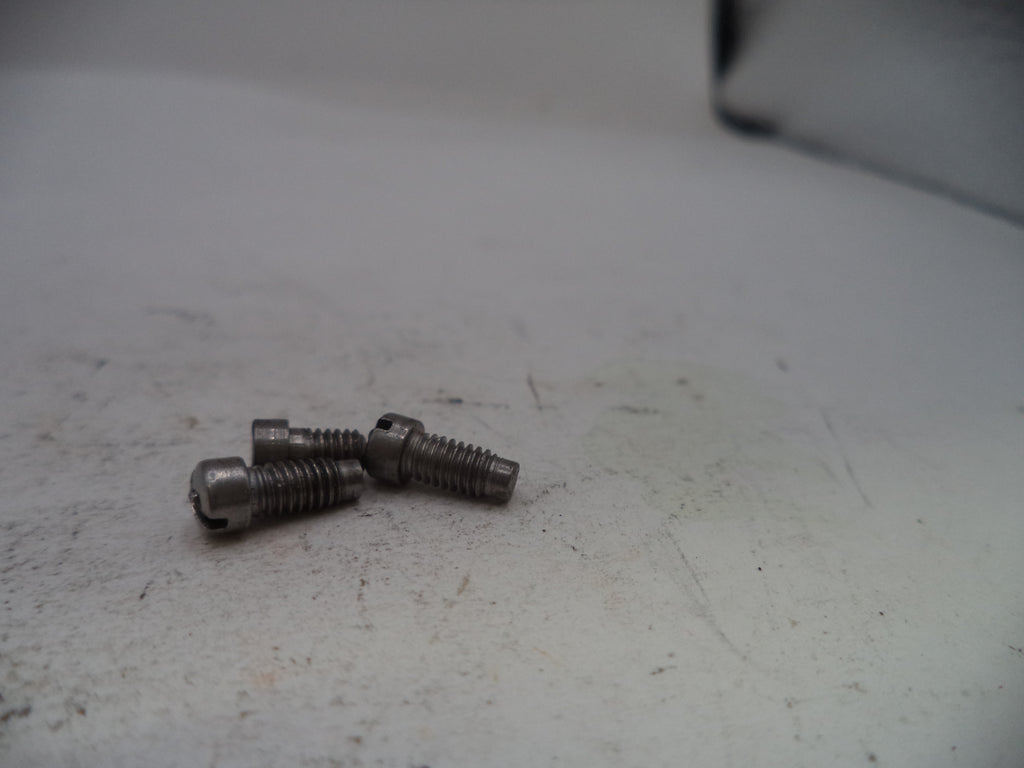 Three metal screws on a scratched white surface