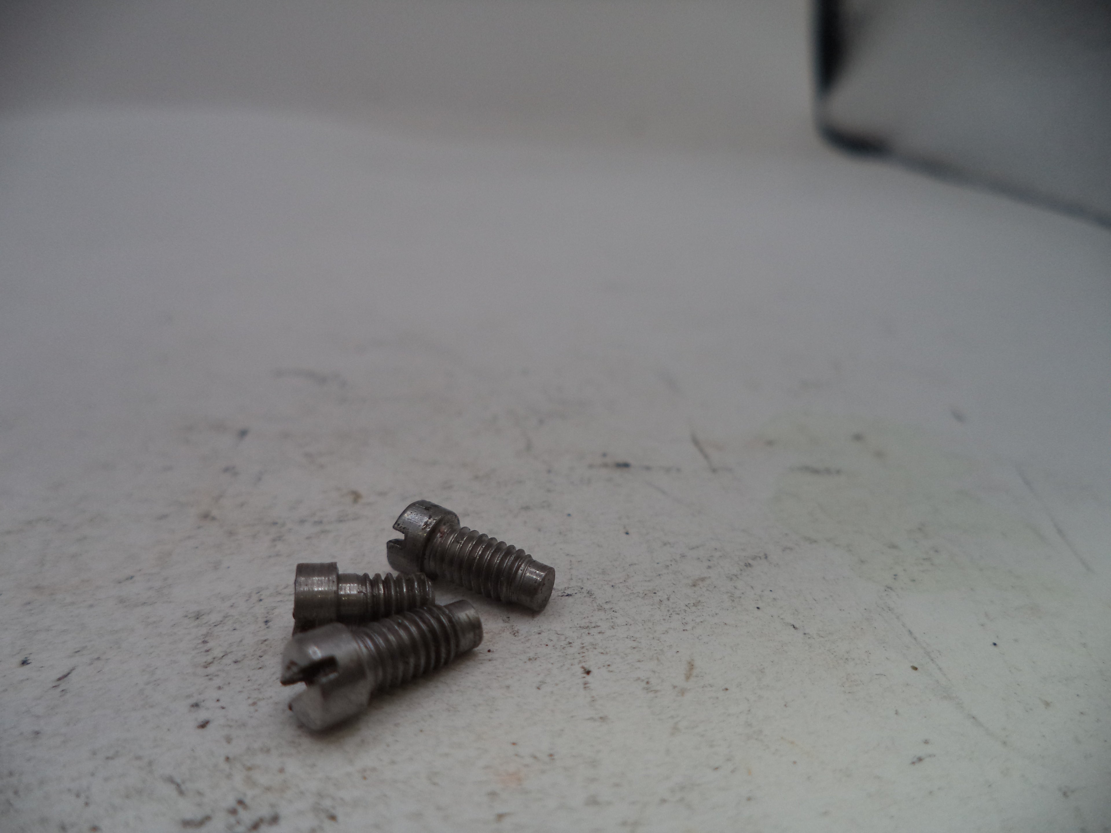 Three metal screws on a worn surface