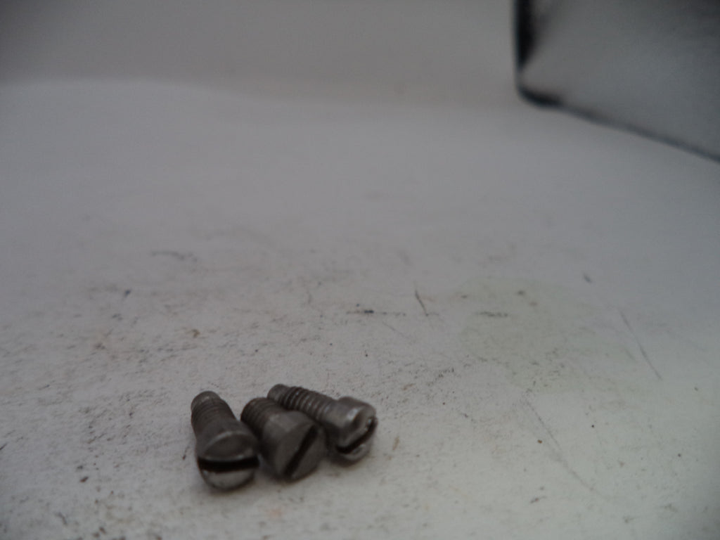 Three metal screws on a white surface with a blurred background