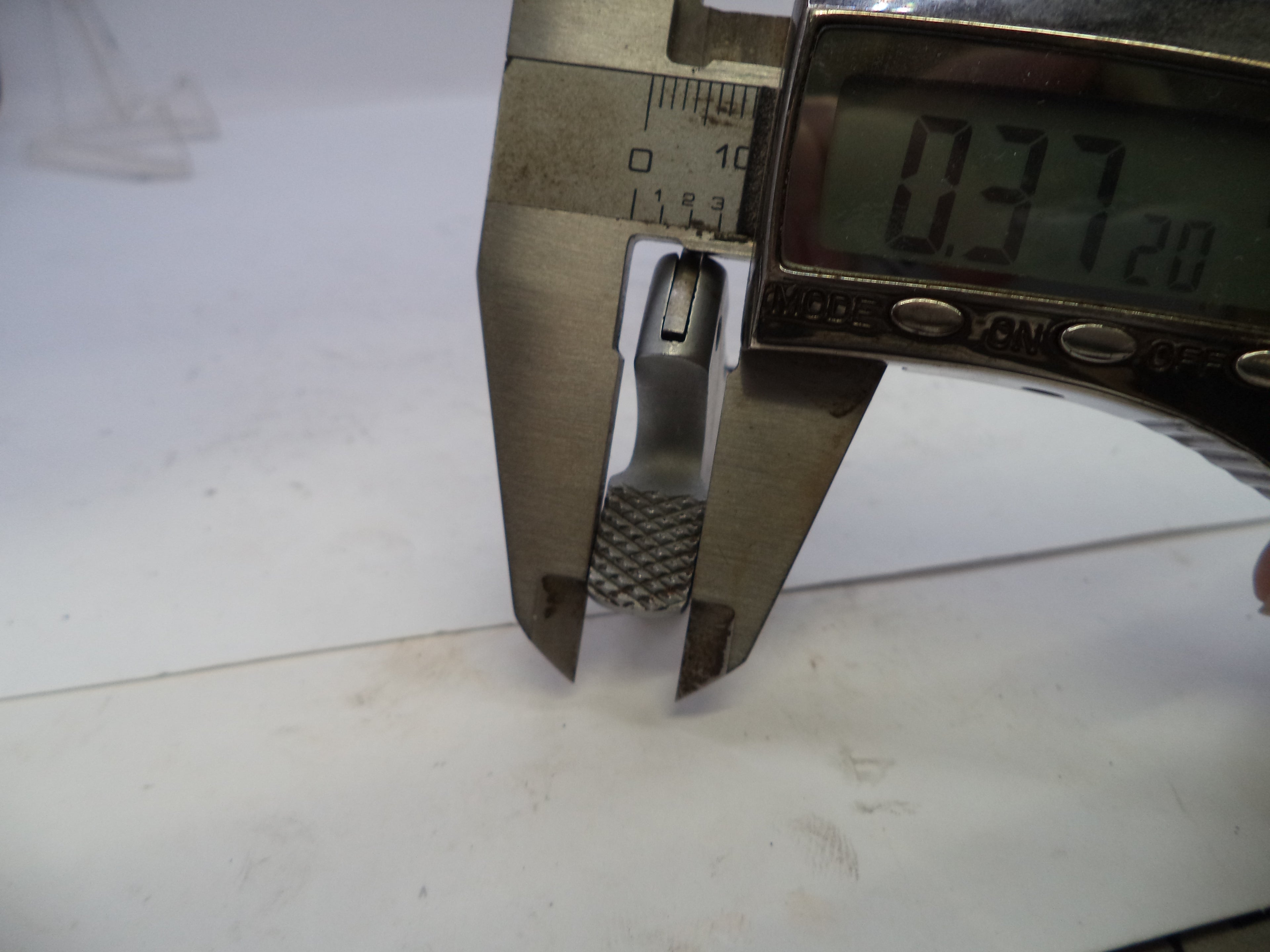 Digital caliper measuring a small object on a white background