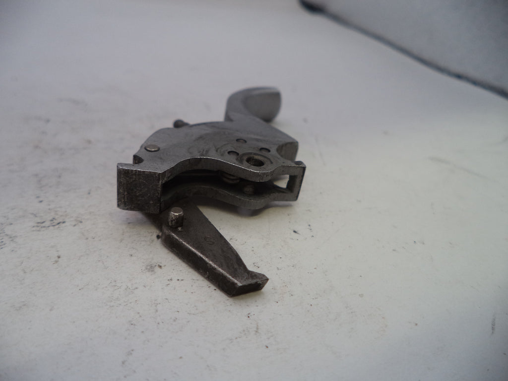 Metallic firearm part on a light gray surface