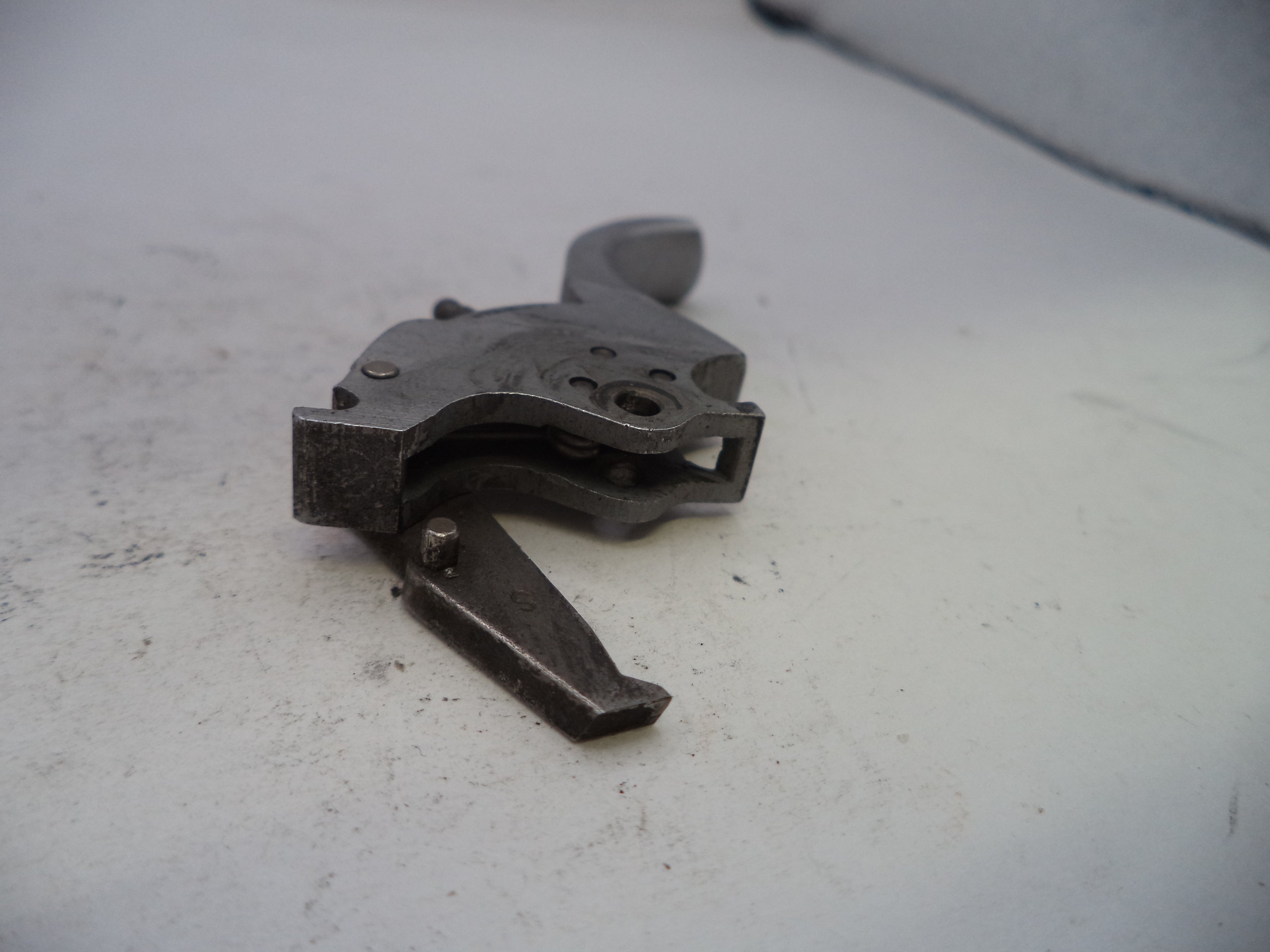 Metallic firearm part on a light gray surface