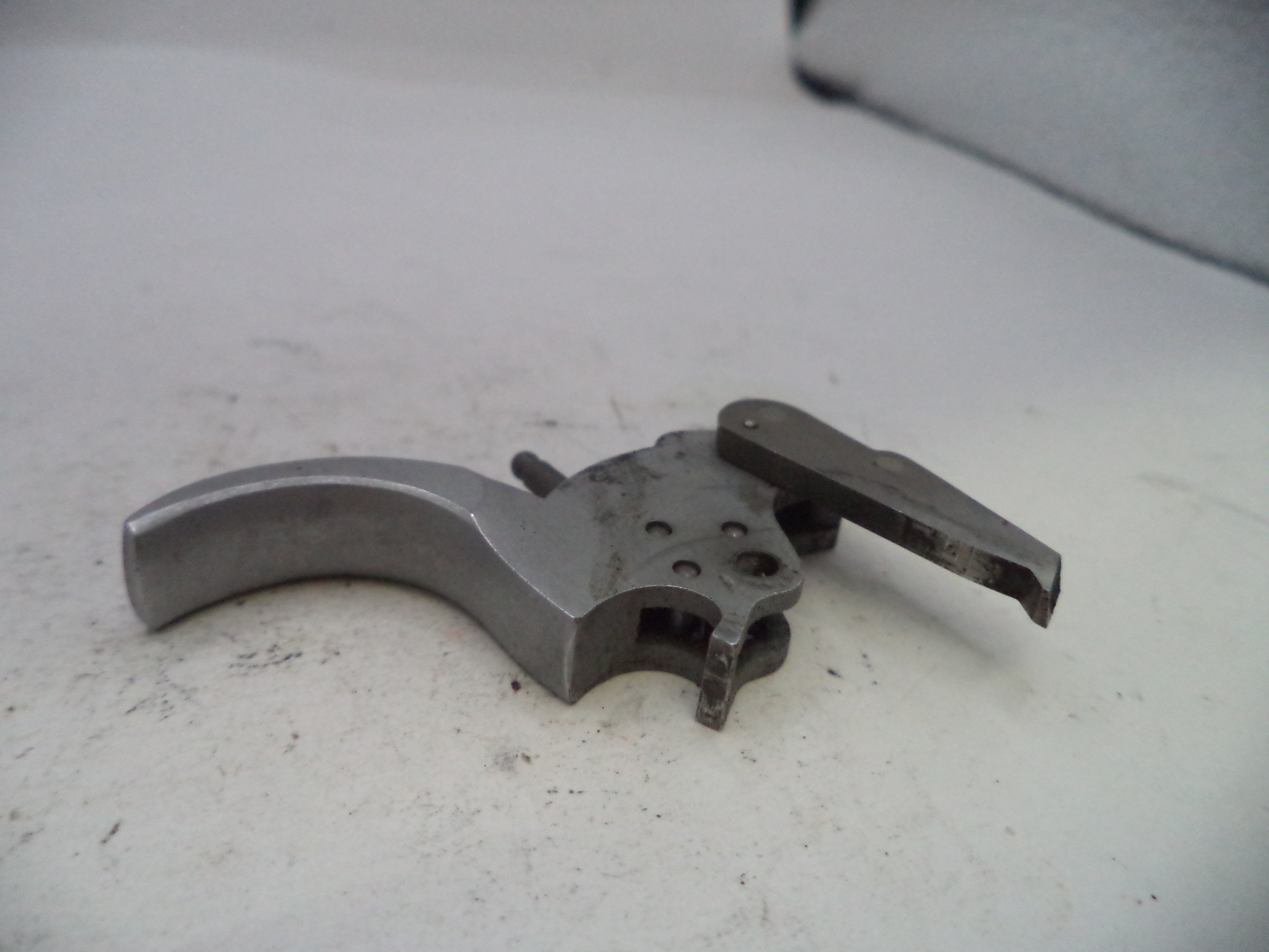 Metallic firearm trigger mechanism on a light gray surface